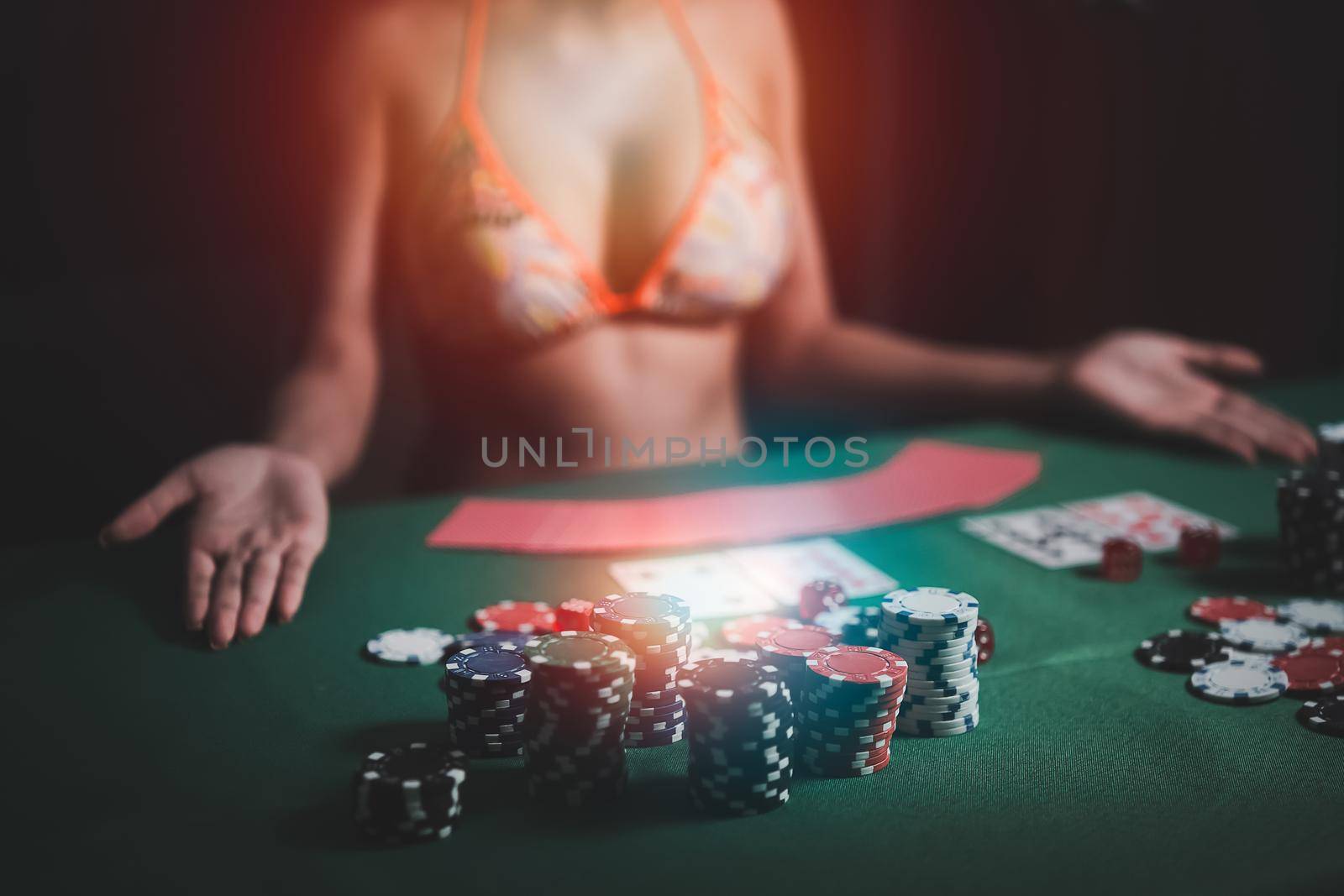 Woman wearing bikini dealer or croupier shuffles poker cards in a casino on the background of a table,asain woman holding two playing cards. Casino, poker, poker game concept by Wmpix