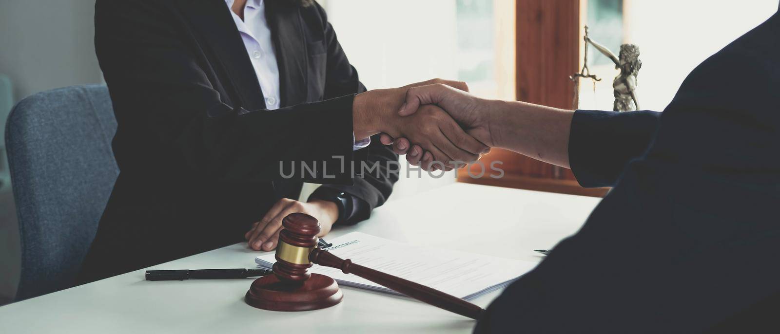 Businessman shaking hands to seal a deal with his partner lawyers or attorneys discussing a contract agreement. by wichayada