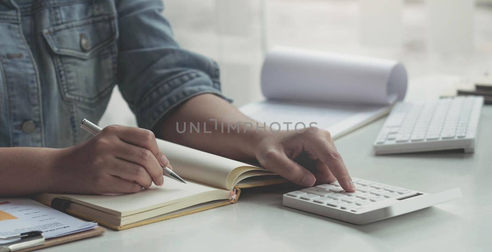 Close up asian woman working with financial data hand using calculator and writing make note with calculate. Business financial and accounting concept..