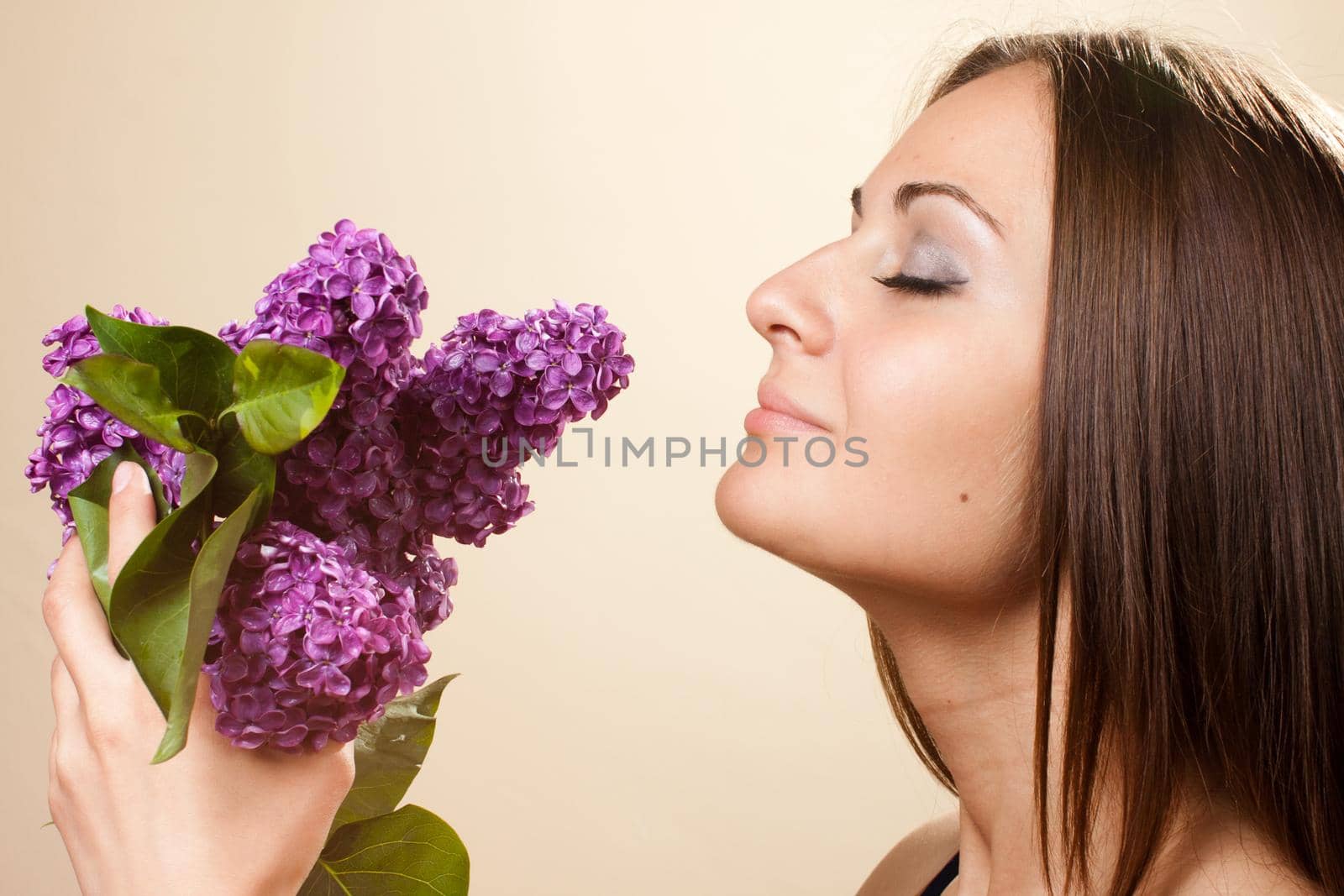 Beautiful young girl weared in black dress with a bouquet of lilac. Spring flowers concept.