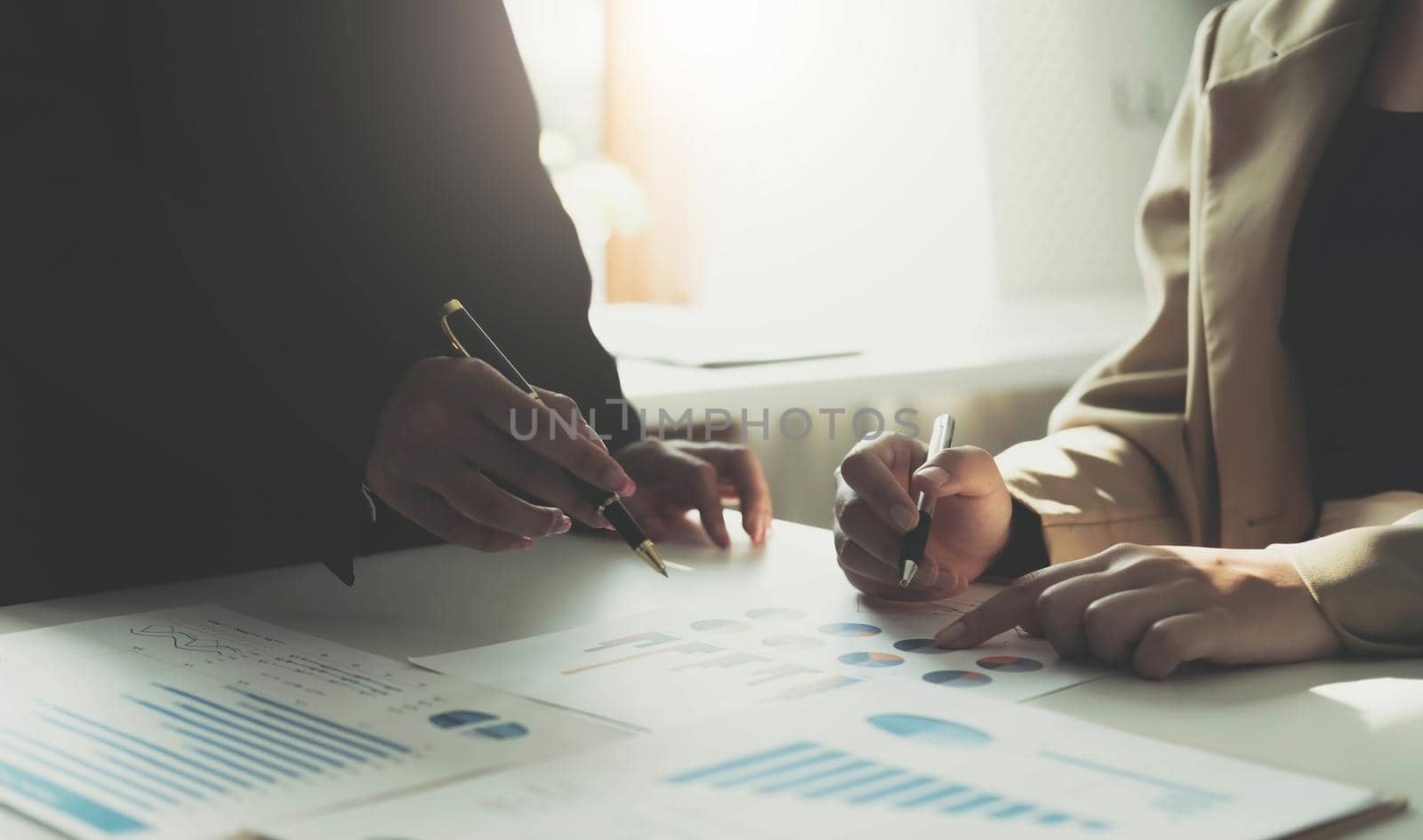 Hands of two young financiers sitting by workplace and discussing financial papers and data at working meeting by wichayada