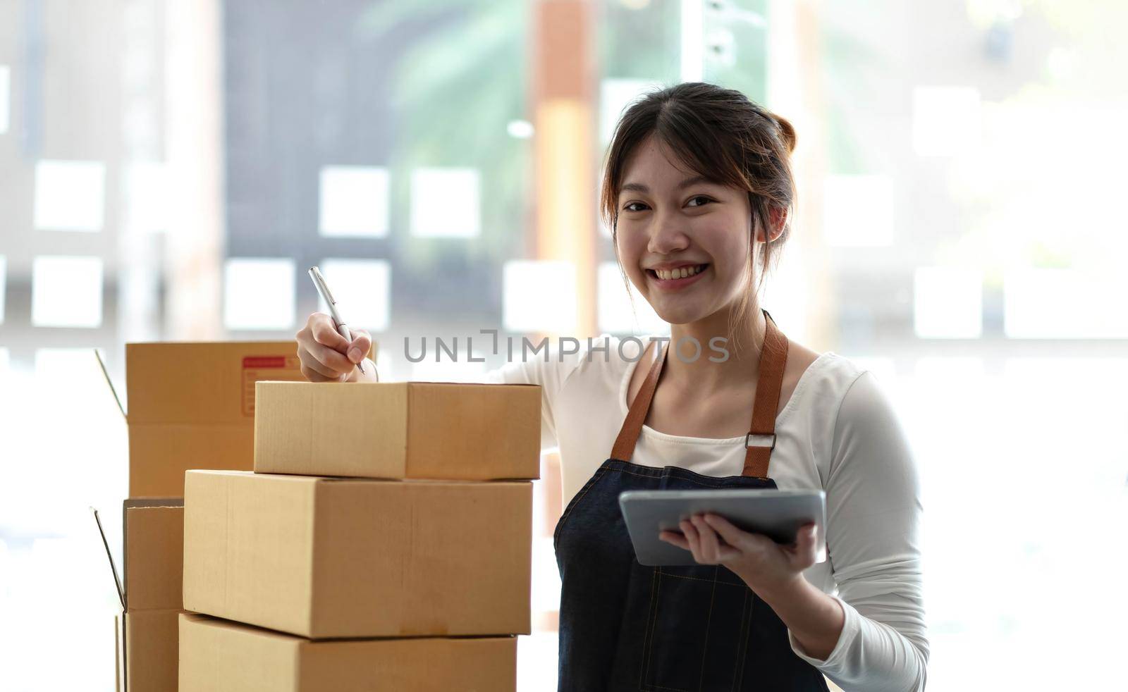 Portrait of Starting small businesses SME owners female entrepreneurs working on receipt box and check online orders to prepare to pack the boxes, sell to customers, sme business ideas online. by wichayada