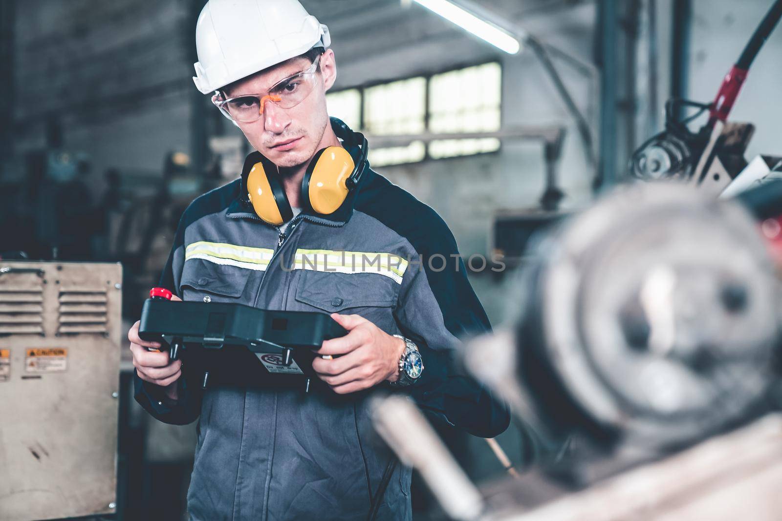 Young factory worker working with adept robotic arm in a workshop . Industry robot programming software for automated manufacturing technology .