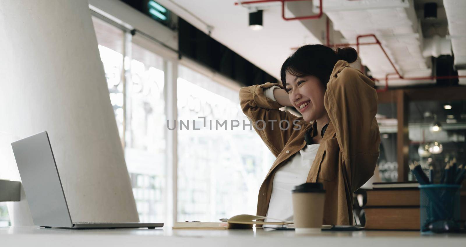 Freelance business women casual wear using tablet working call video conference with customer in workplace in living room at home. Happy young Asian girl relax sitting on desk do job in internet..