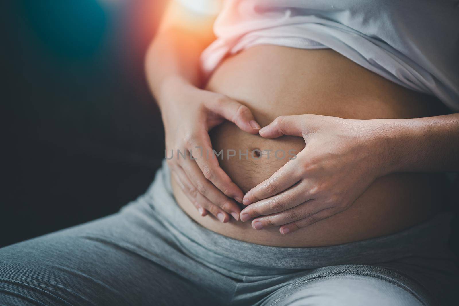 Pregnant woman holding hands in heart shape on belly at home.pregnant woman making heart with her hands, closeup.