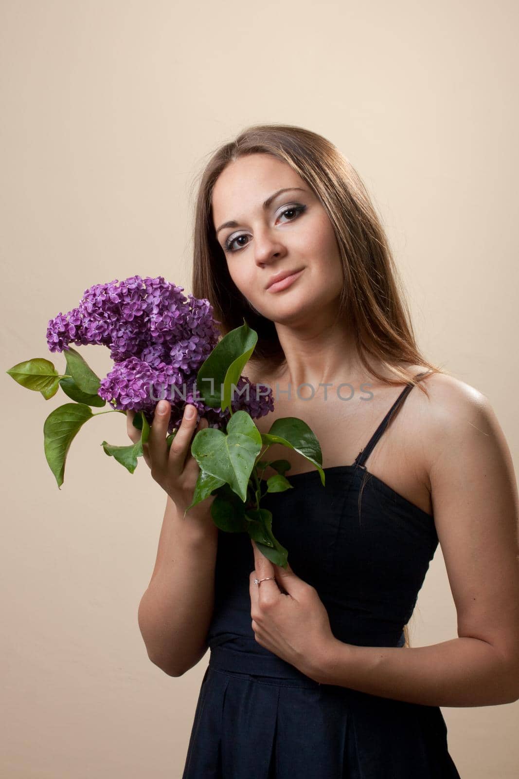 Beautiful young girl weared in black dress with a bouquet of lilac. Spring flowers concept.