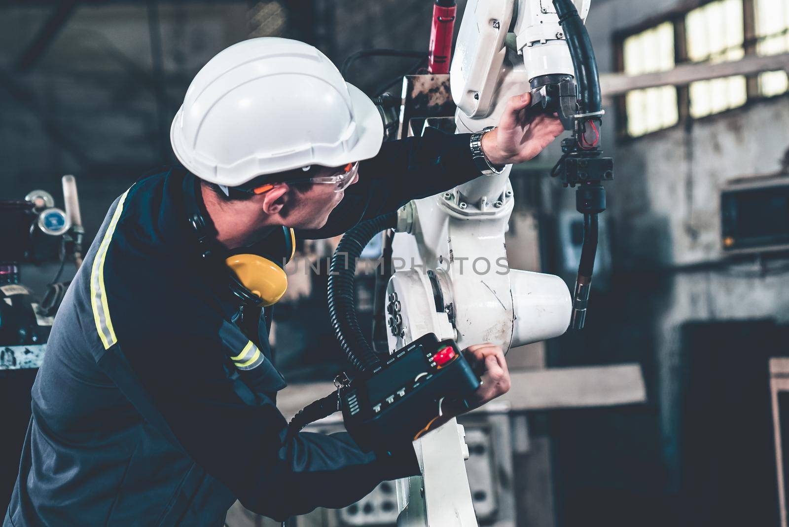 Young factory worker working with adept robotic arm in a workshop . Industry robot programming software for automated manufacturing technology .