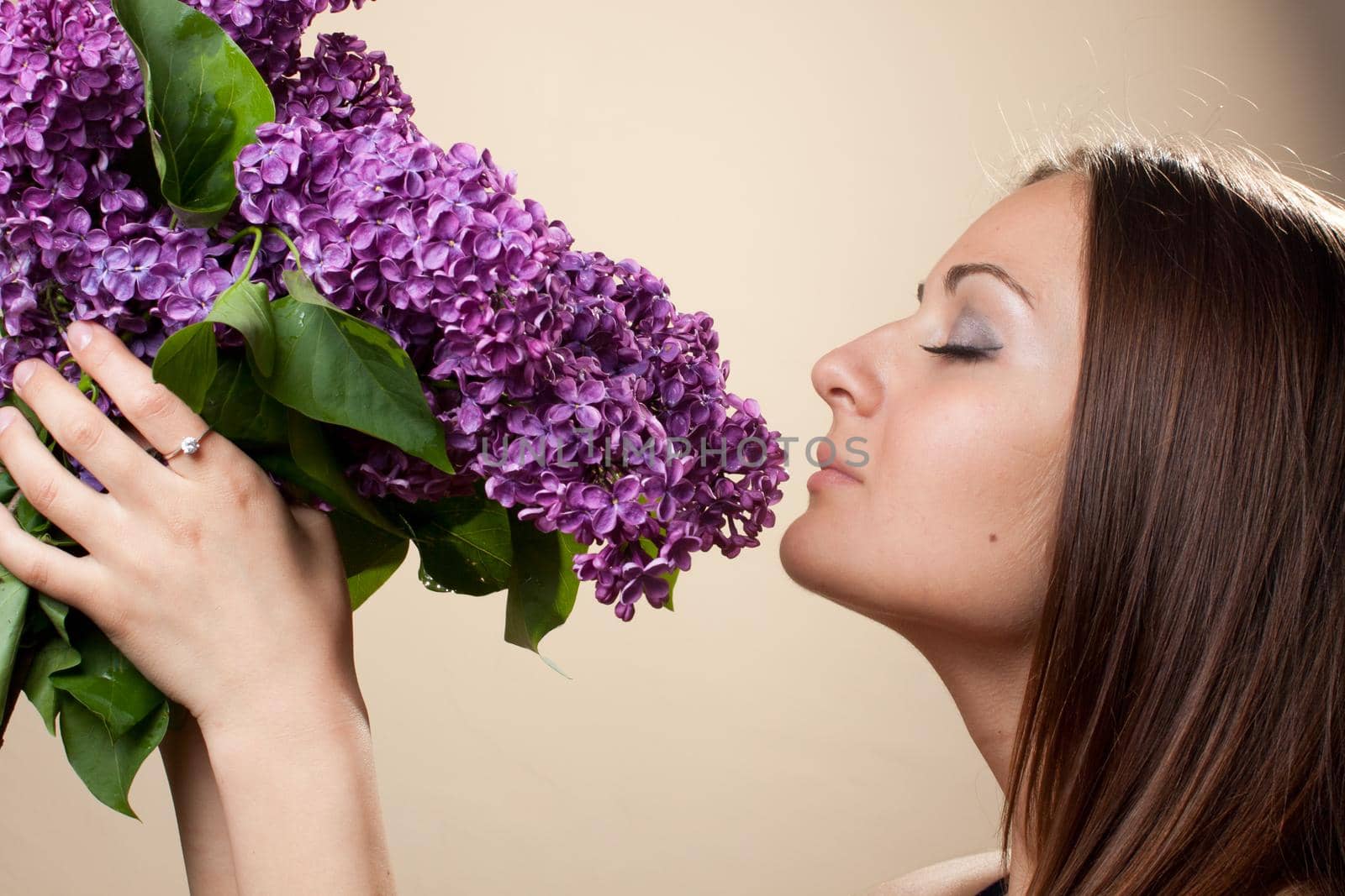 Beautiful young girl weared in black dress with a bouquet of lilac. Spring flowers concept.