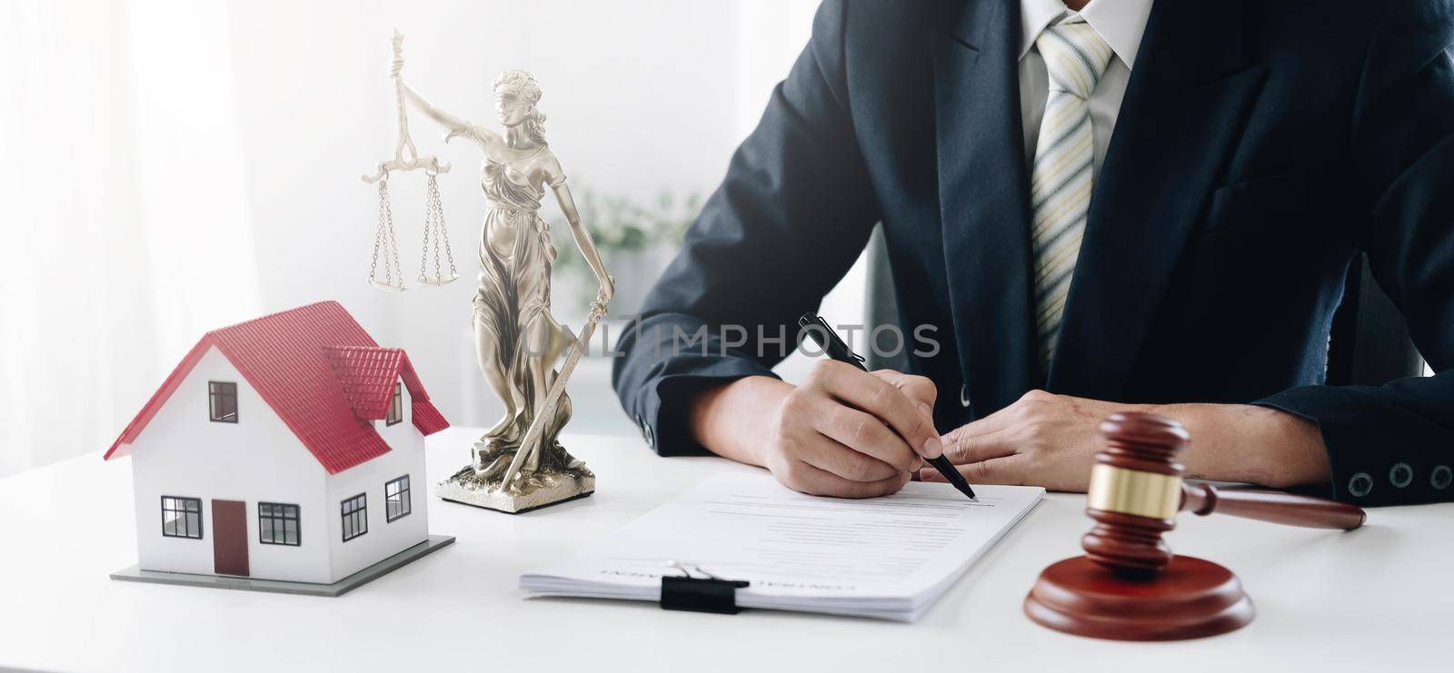Judge gavel and house model on the table. Man signing in document. Real Estate Lawyer.