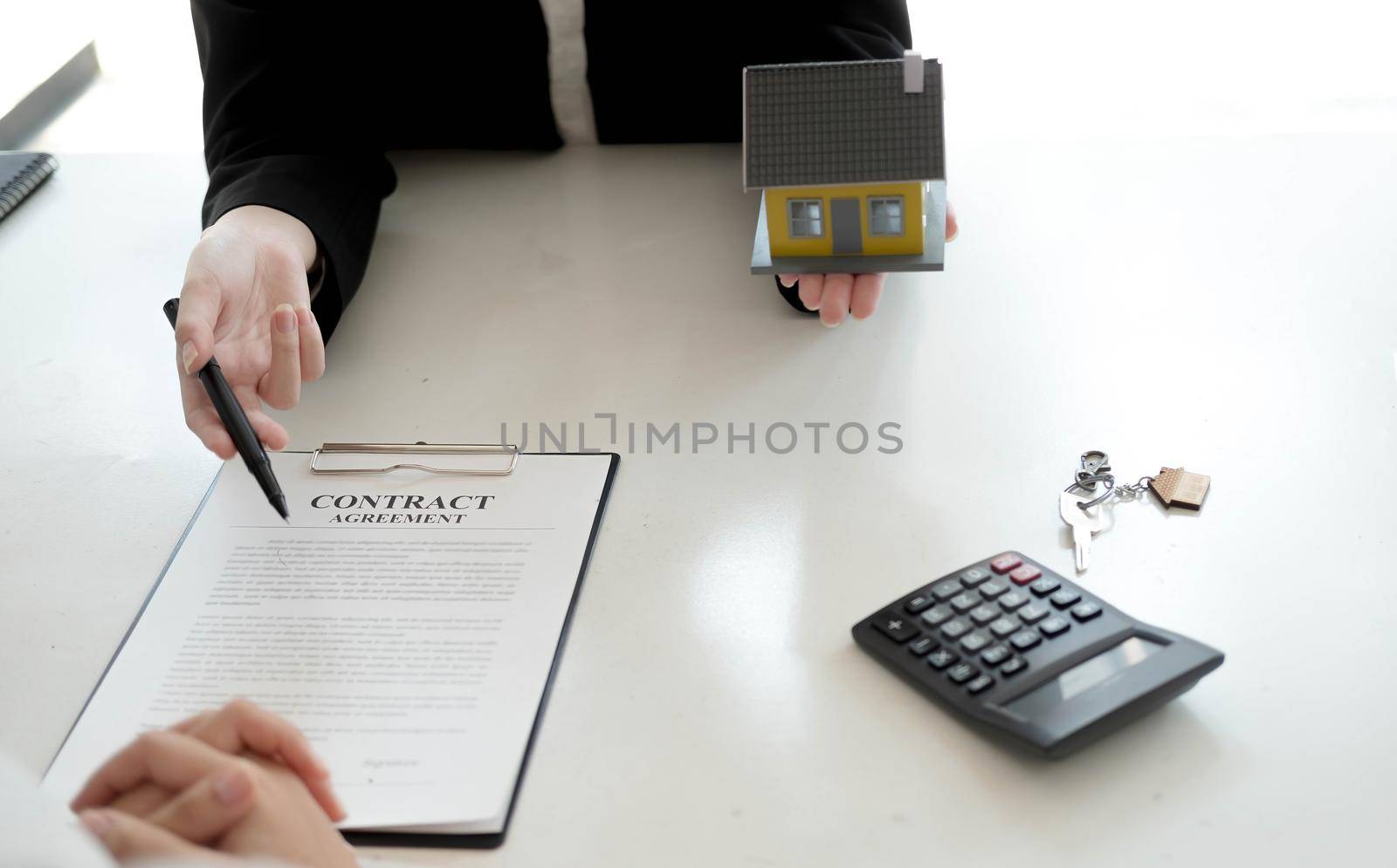 Property sales staff submit land mortgage contract documents to home buyers for sign. by wichayada