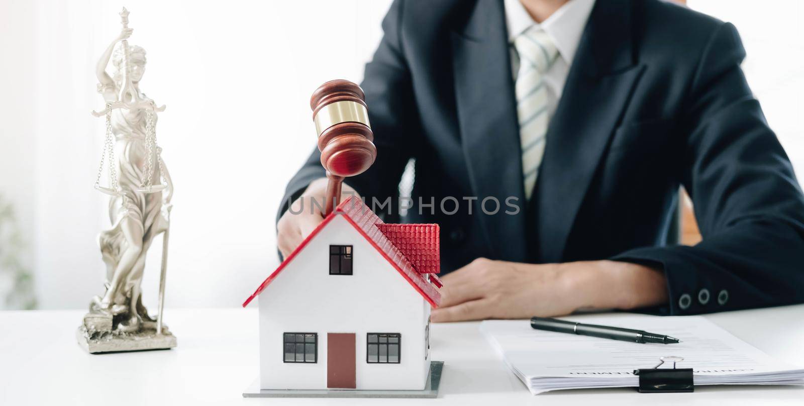 Businessman hand hold old wood Judge hammer with Mini wood house model from model on wood table, Planning buy Real Estate, Planning to buy property and Choose the best, financial liabilities concept..