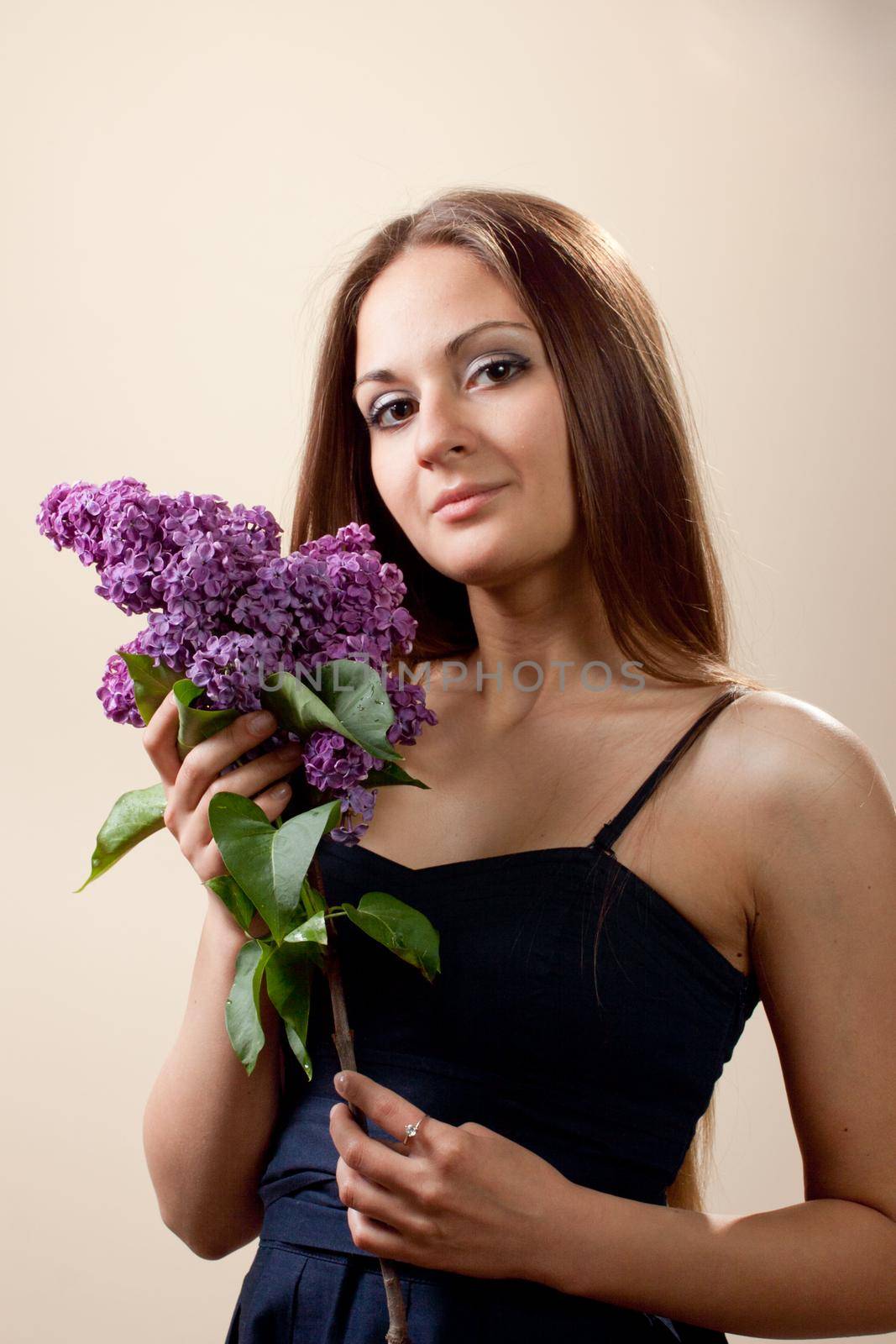 Beautiful young girl weared in black dress with a bouquet of lilac. Spring flowers concept.