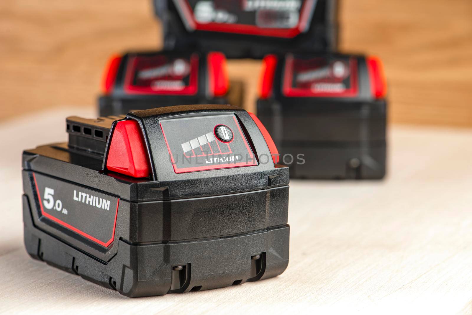 Battery for cordless drill. Screwdriver battery. Four batteries with a charge indicator lie on a wooden background.