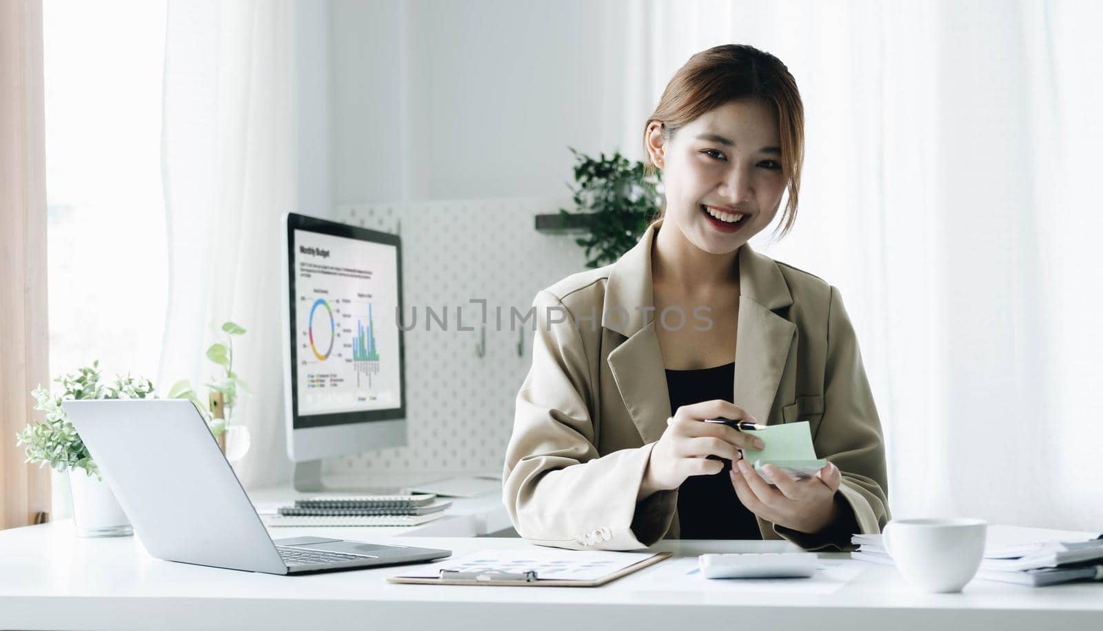 Portrait of confident young entrepreneur sitting at modern workplace and smiling to camera. by wichayada