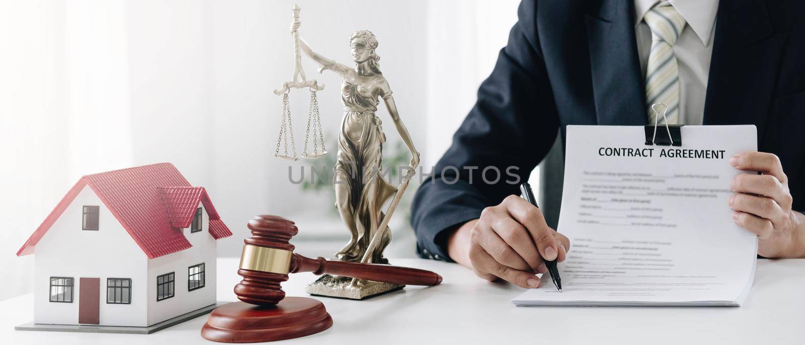 Judge gavel and house model on the table. Man signing in document. Real Estate Lawyer by wichayada