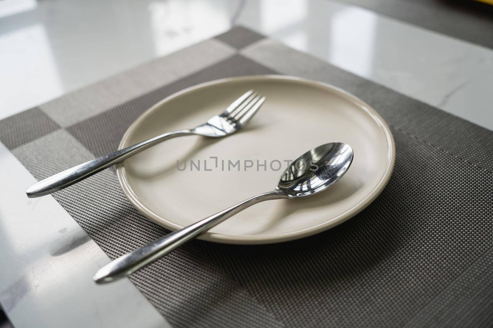 empty plate spoon and fork on table in restaurant. by Wmpix