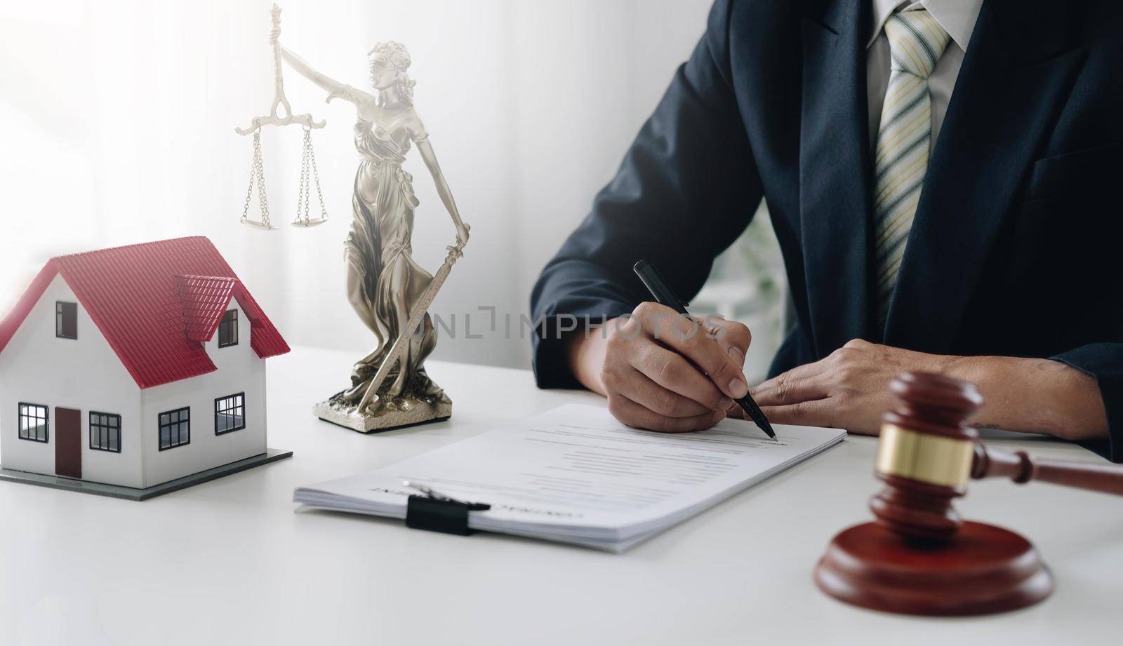 Judge gavel and house model on the table. Man signing in document. Real Estate Lawyer by wichayada