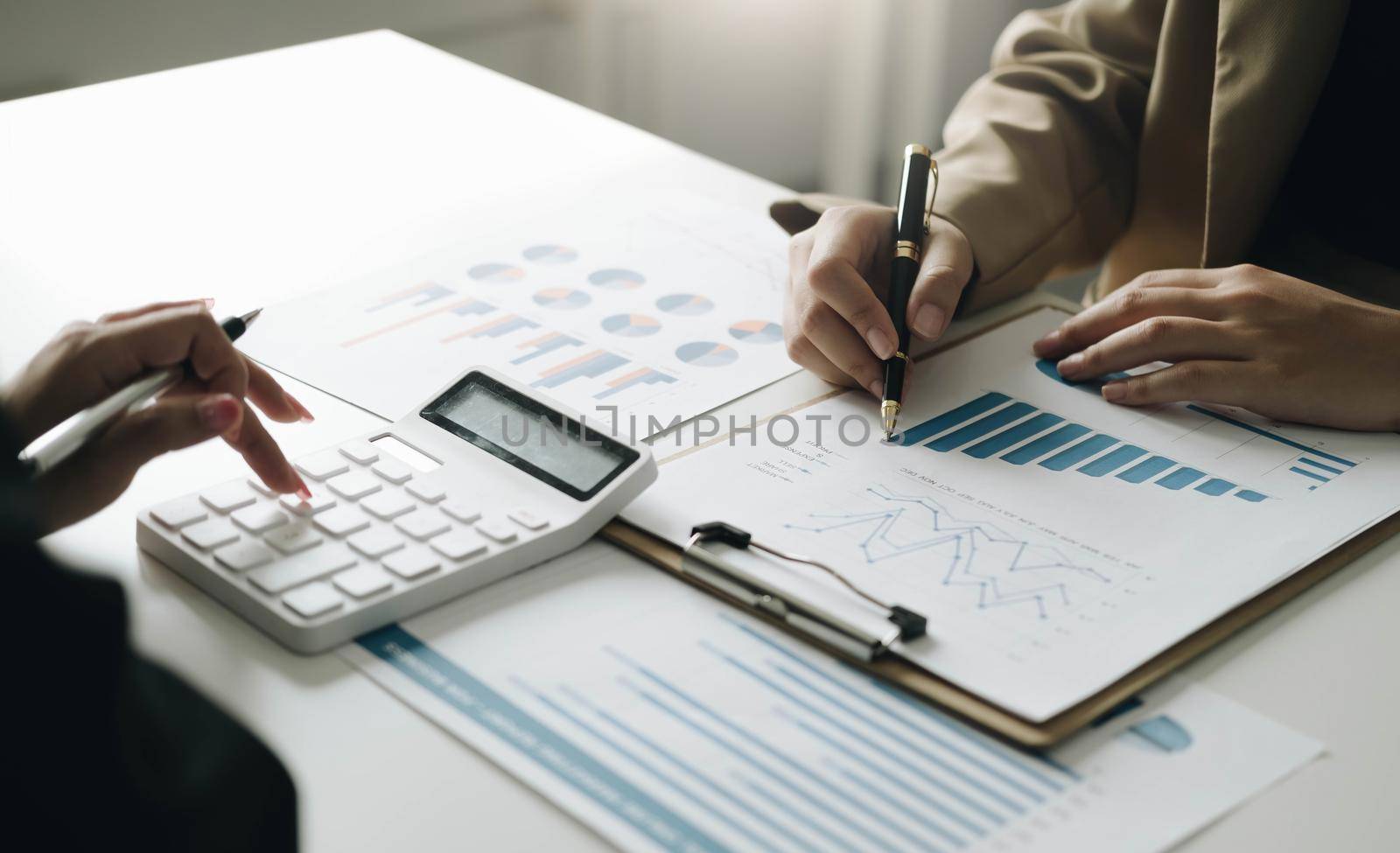 Close-up Hands of two young woman accountant use calculator with holding pen and point report in the office . finance and accounting concept.