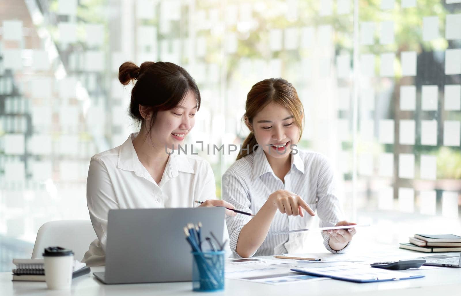 Two Young Asian businesswoman discuss with new startup project Idea presentation, analyze planning and financial statistics and investment market at office..