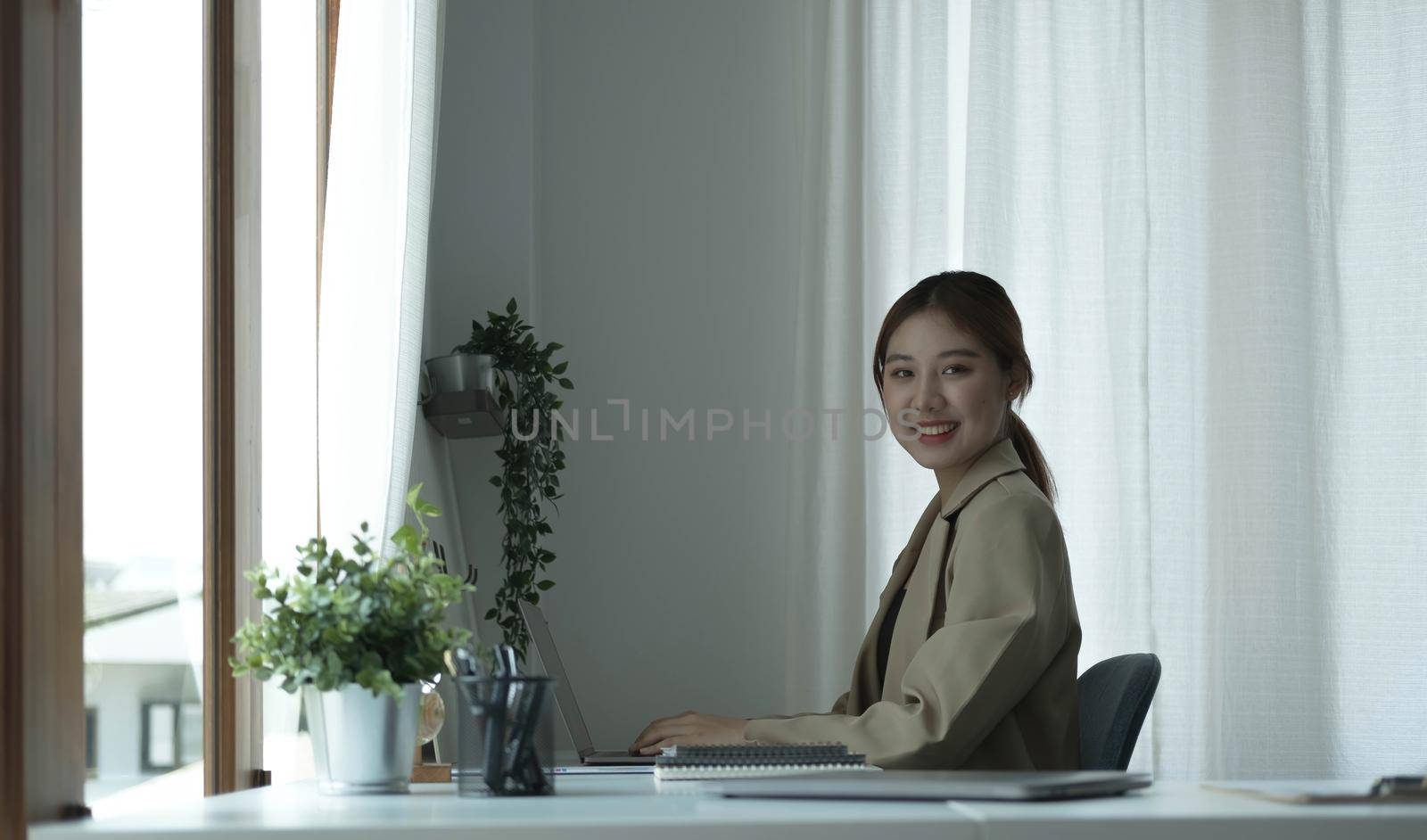 Portrait of confident young entrepreneur sitting at modern workplace and smiling to camera..