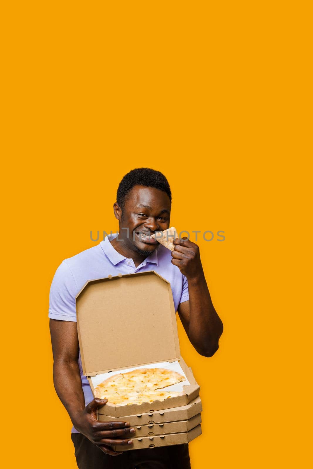 Funny black courier laughts and holds piece of pizza with 4 pizza boxes. Tasty food pizza delivery from restaurant. Safety delivery