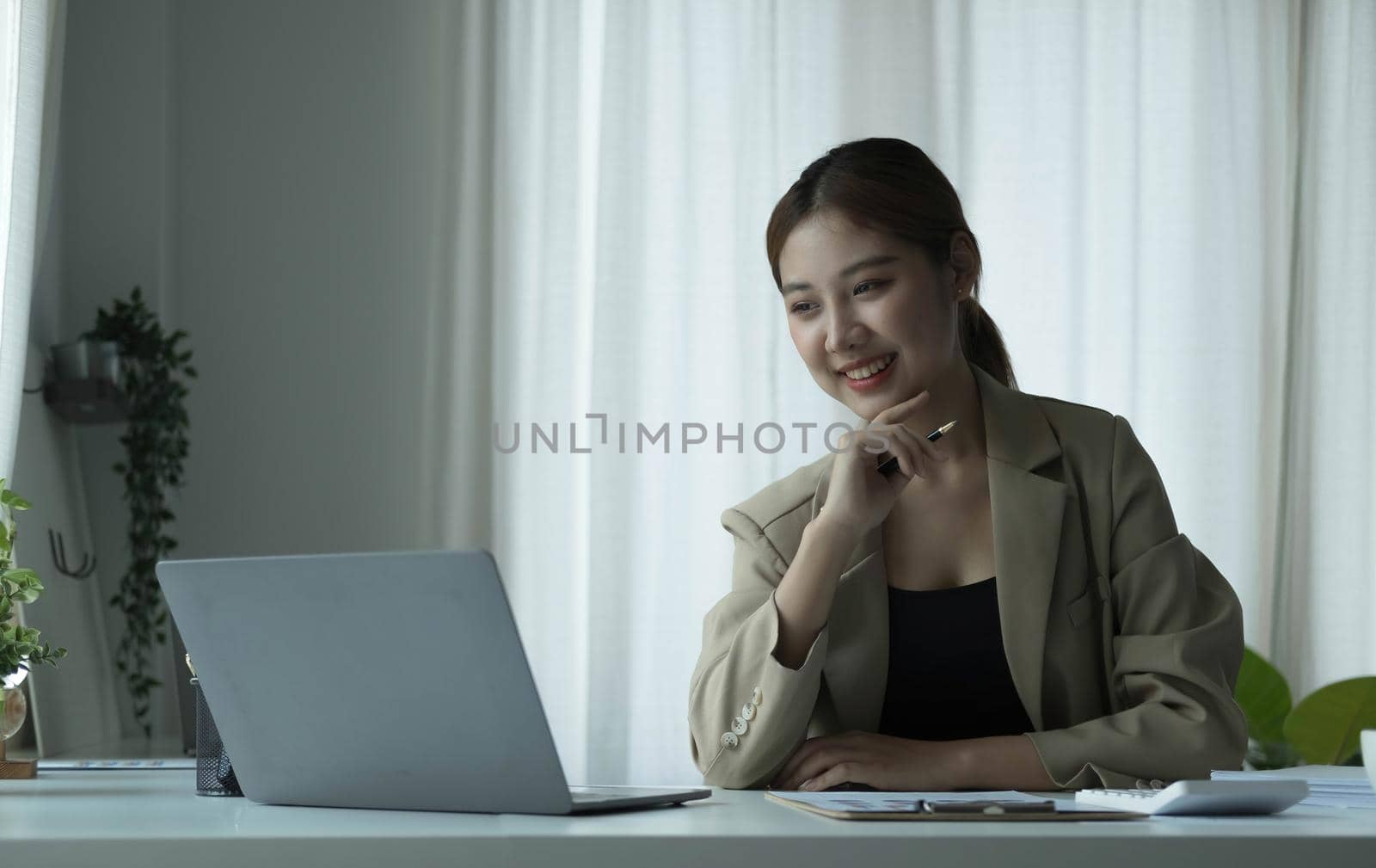 Young Asian businesswoman is happy to work at the modern office using a tablet. by wichayada