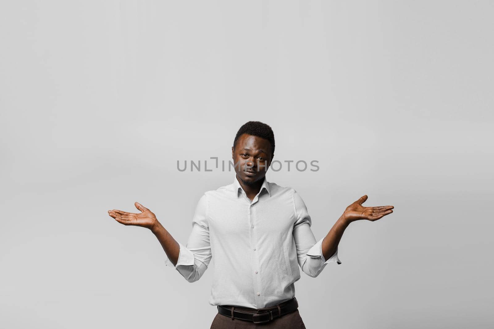 Handsome surprised black man shrugs and gives a choose. Choosing between 2 items. African offers a choice.