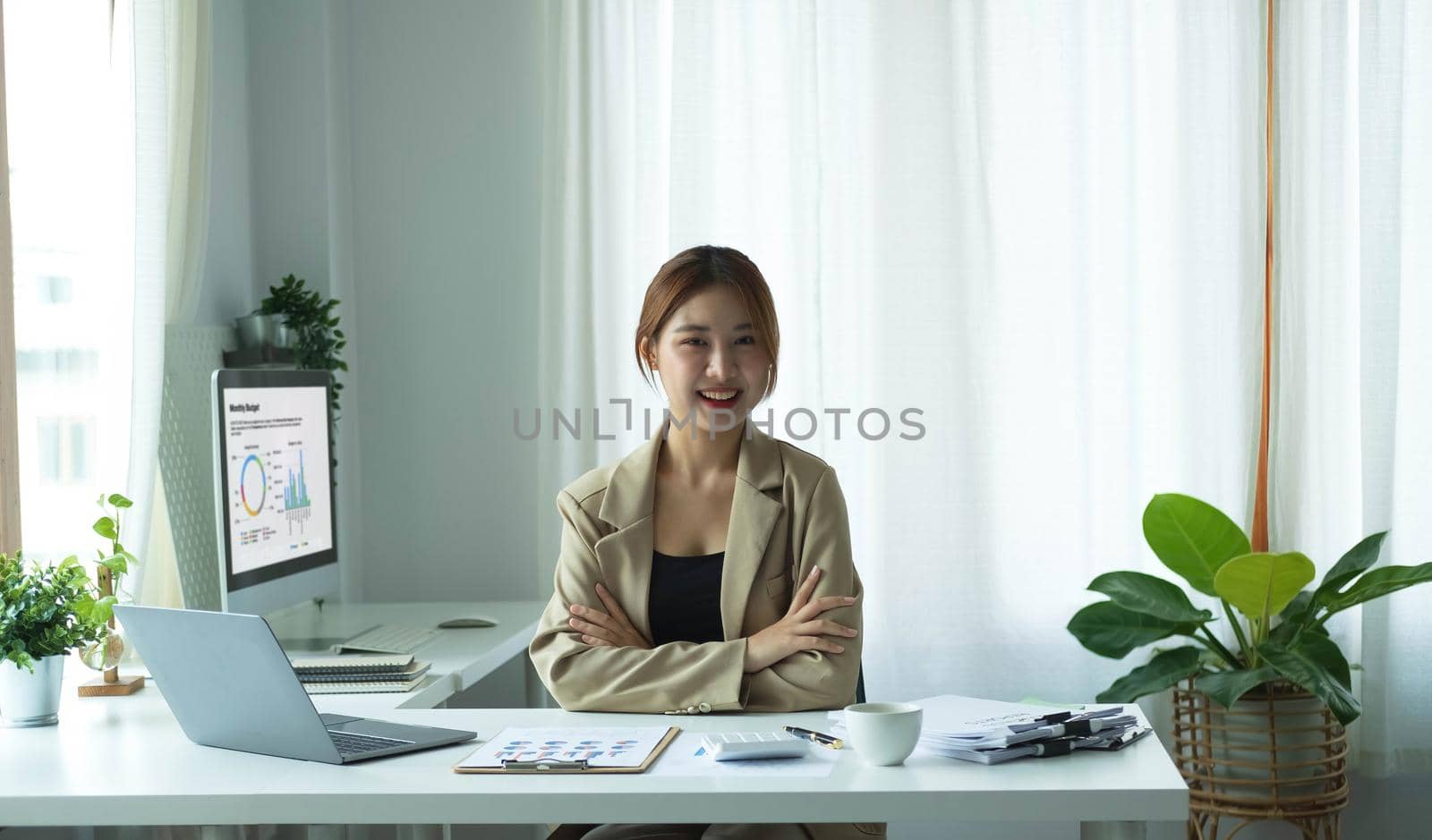 Portrait of confident young entrepreneur sitting at modern workplace and smiling to camera. by wichayada