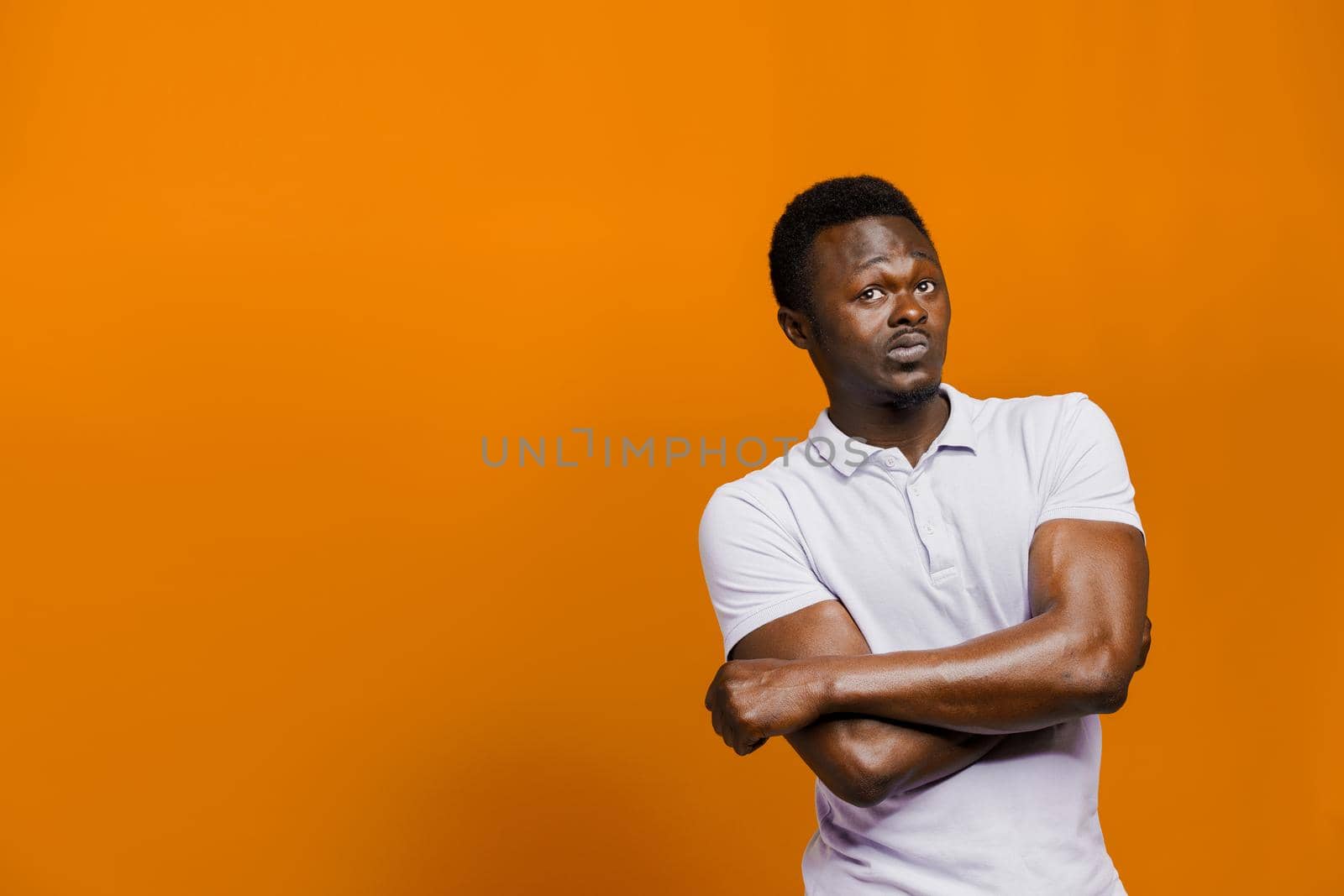 Big discount for our customers. Funny black man points right side and grimacing on orange background. Smiley people lifestyle.