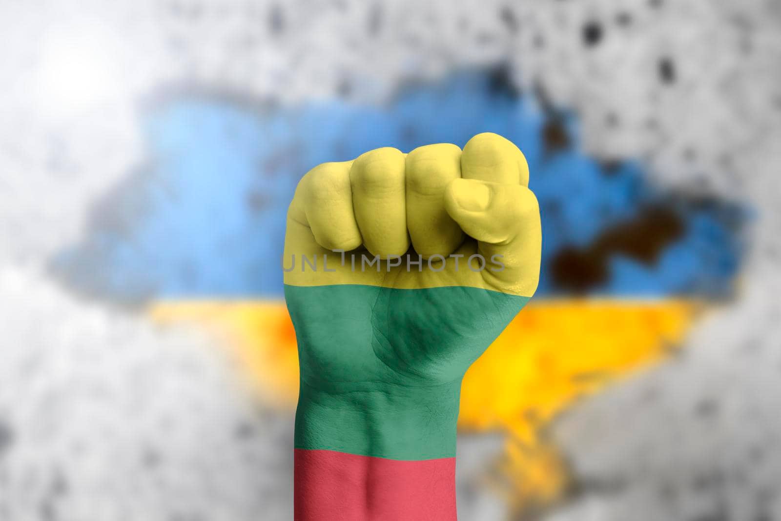 Lithuania helps Ukraine and stands in solidarity with it. The concept of humanitarian aid to Ukraine. The fist is painted in the colors of the Lithuanian flag on the background of the Ukrainian flag