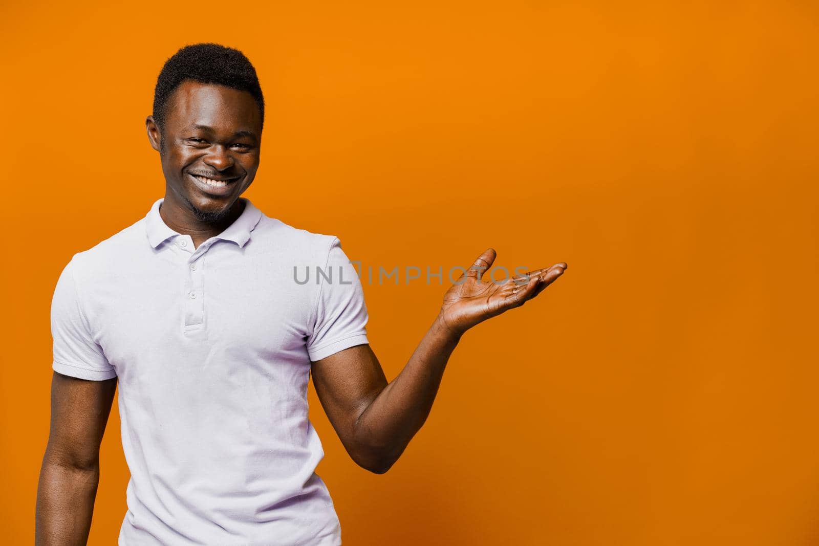 Big discount for our customers. Funny black man points right side and smiles on orange background. Smiley people lifestyle by Rabizo