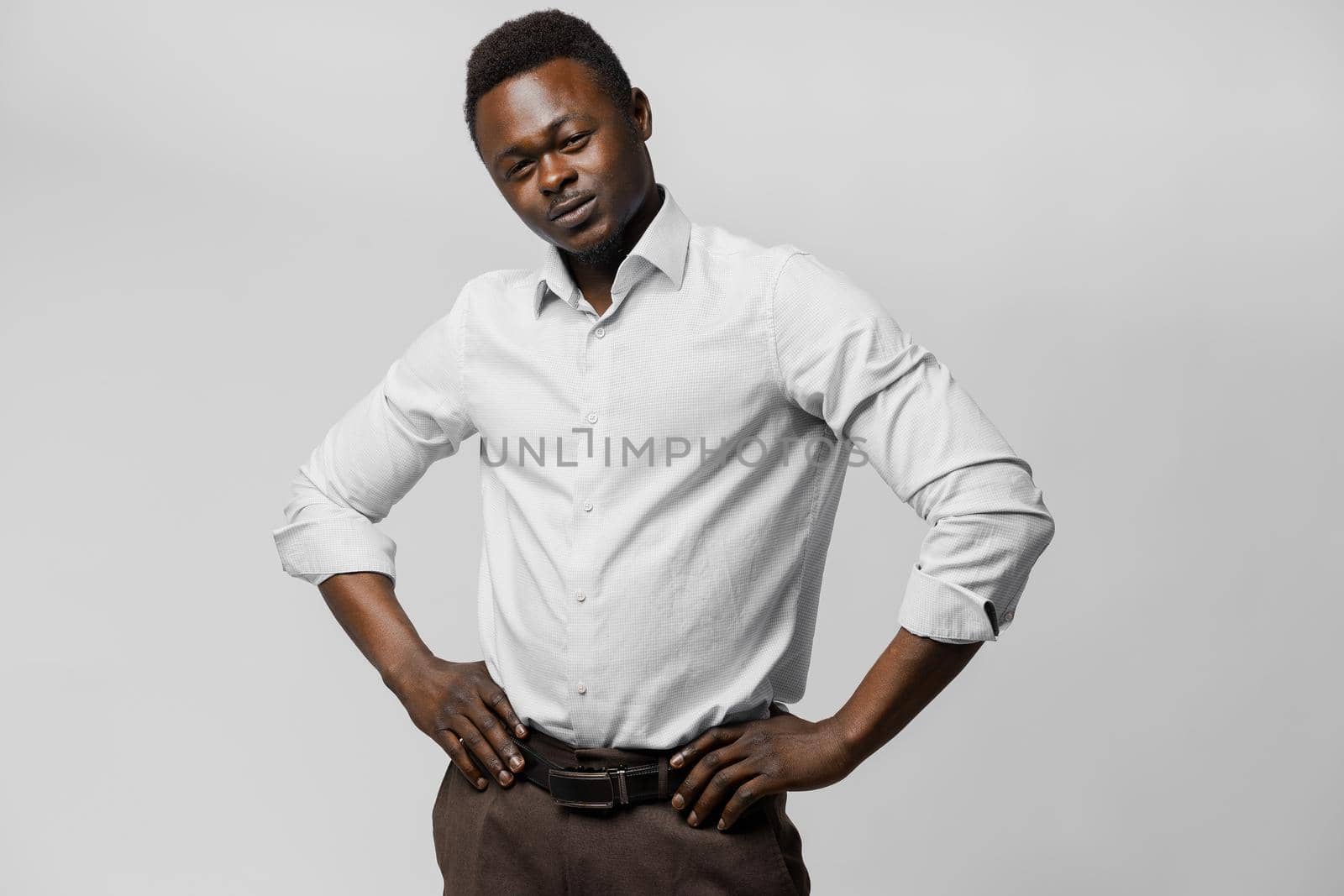 Handsome black african puts his hands on his hips. Business portrait in studio on white background. Online business.