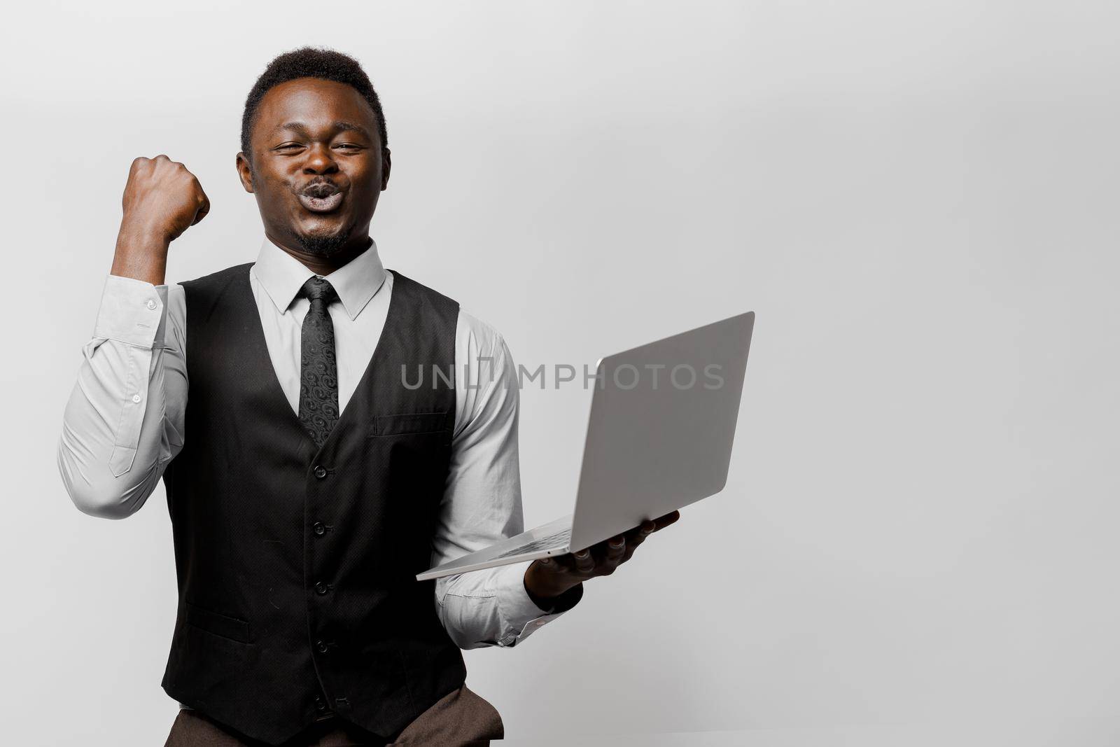 Happy black man wins some money in on-line lottery. African lucky man with laptop on white background. by Rabizo