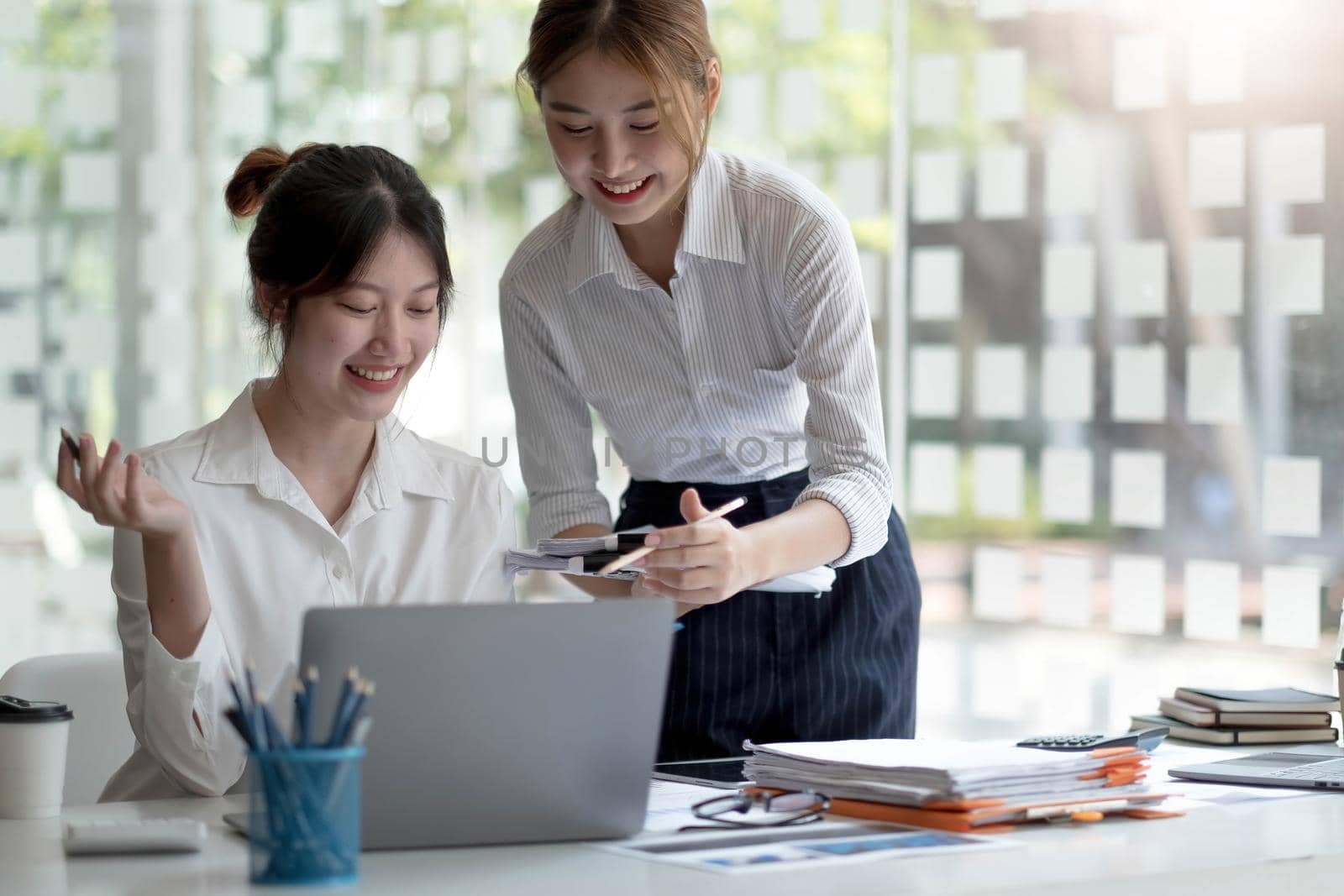 Two Young Asian businesswoman discuss with new startup project Idea presentation, analyze planning and financial statistics and investment market at office..