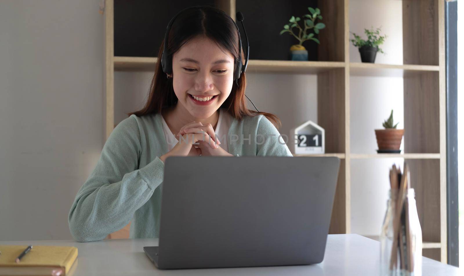 Smart Asian students find satisfaction while studying online on the Internet and meeting with friends to search for information on their laptops at home. by wichayada