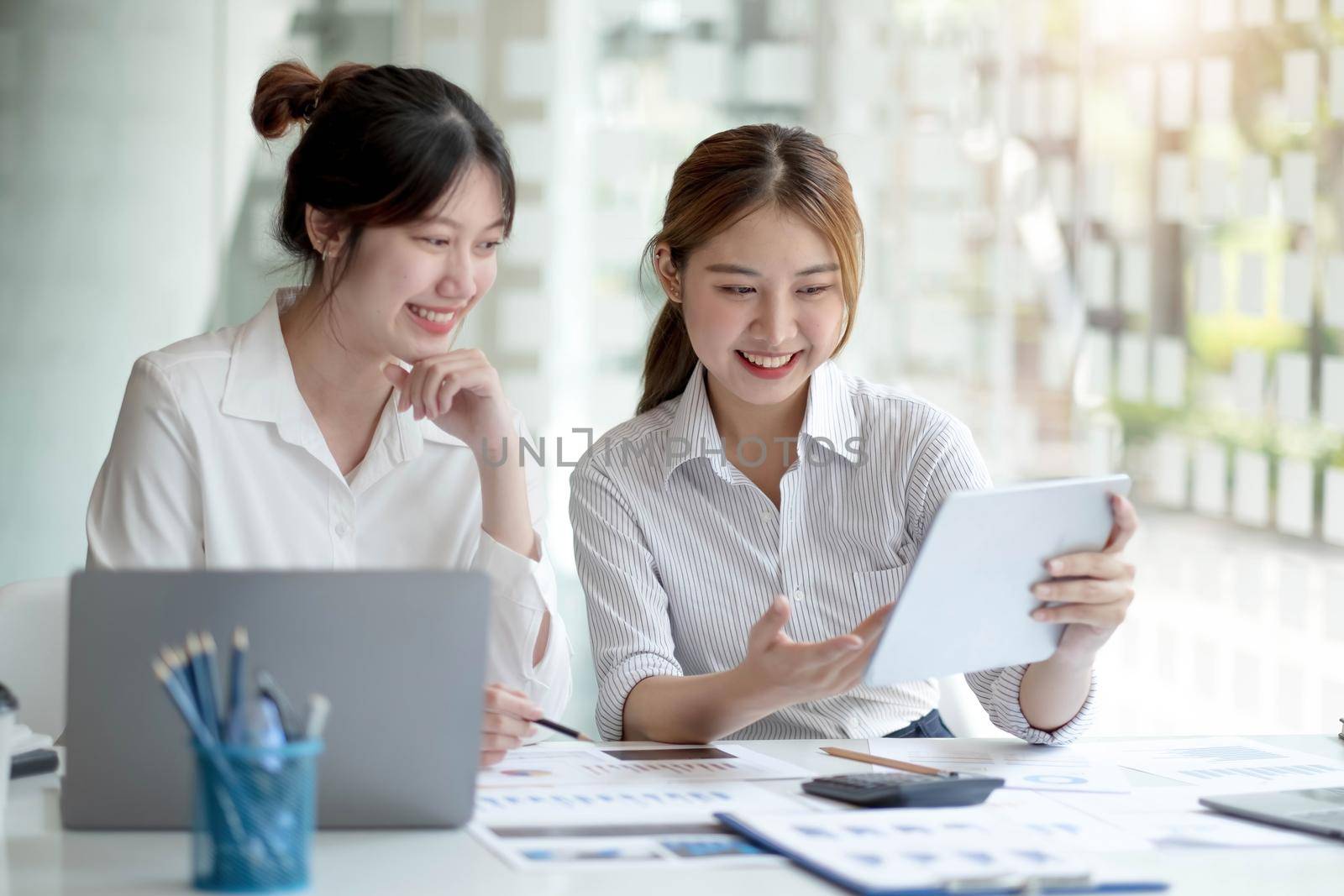 Two Young Asian businesswoman discuss with new startup project Idea presentation, analyze planning and financial statistics and investment market at office..