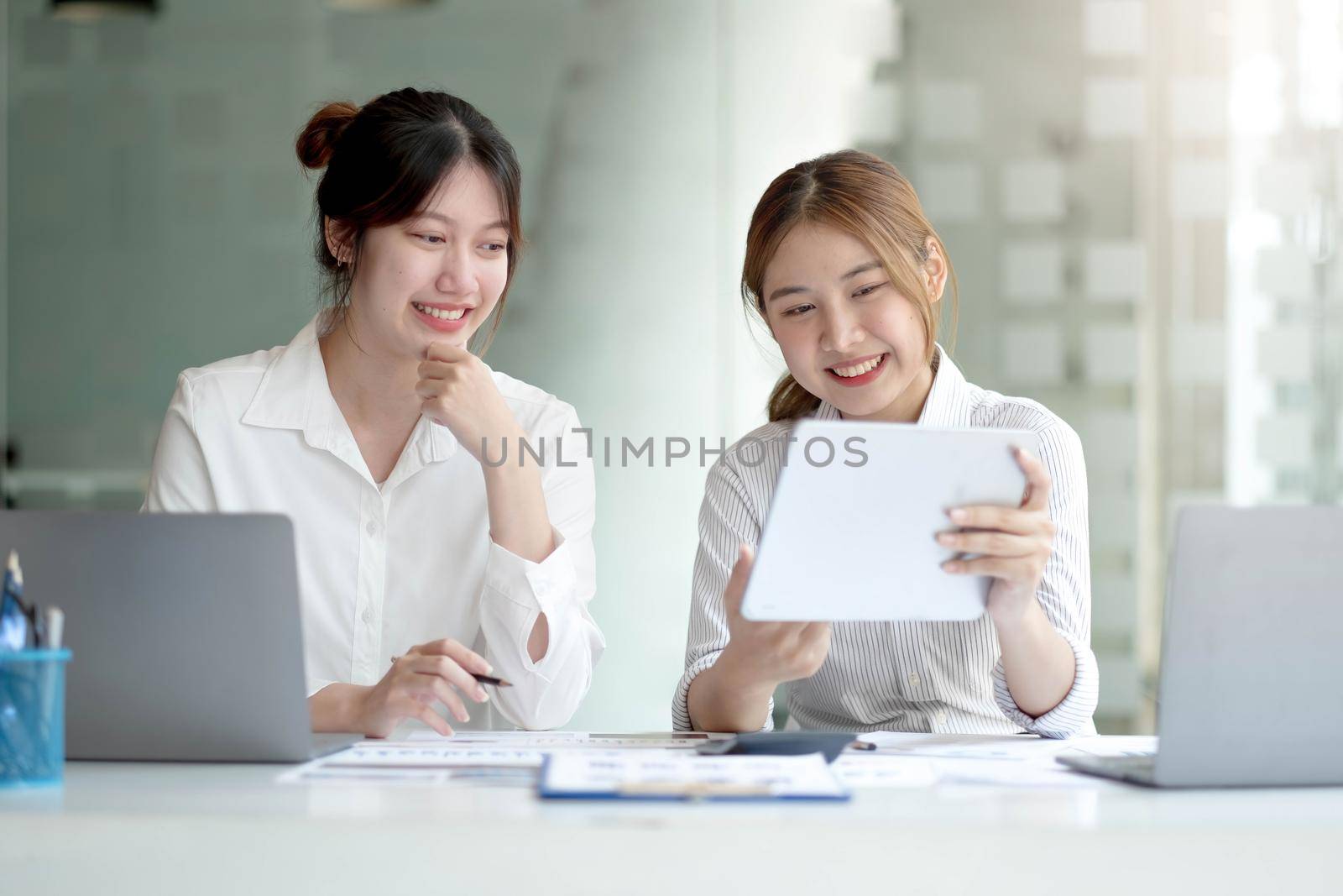 Two Young Asian businesswoman discuss with new startup project Idea presentation, analyze planning and financial statistics and investment market at office. by wichayada