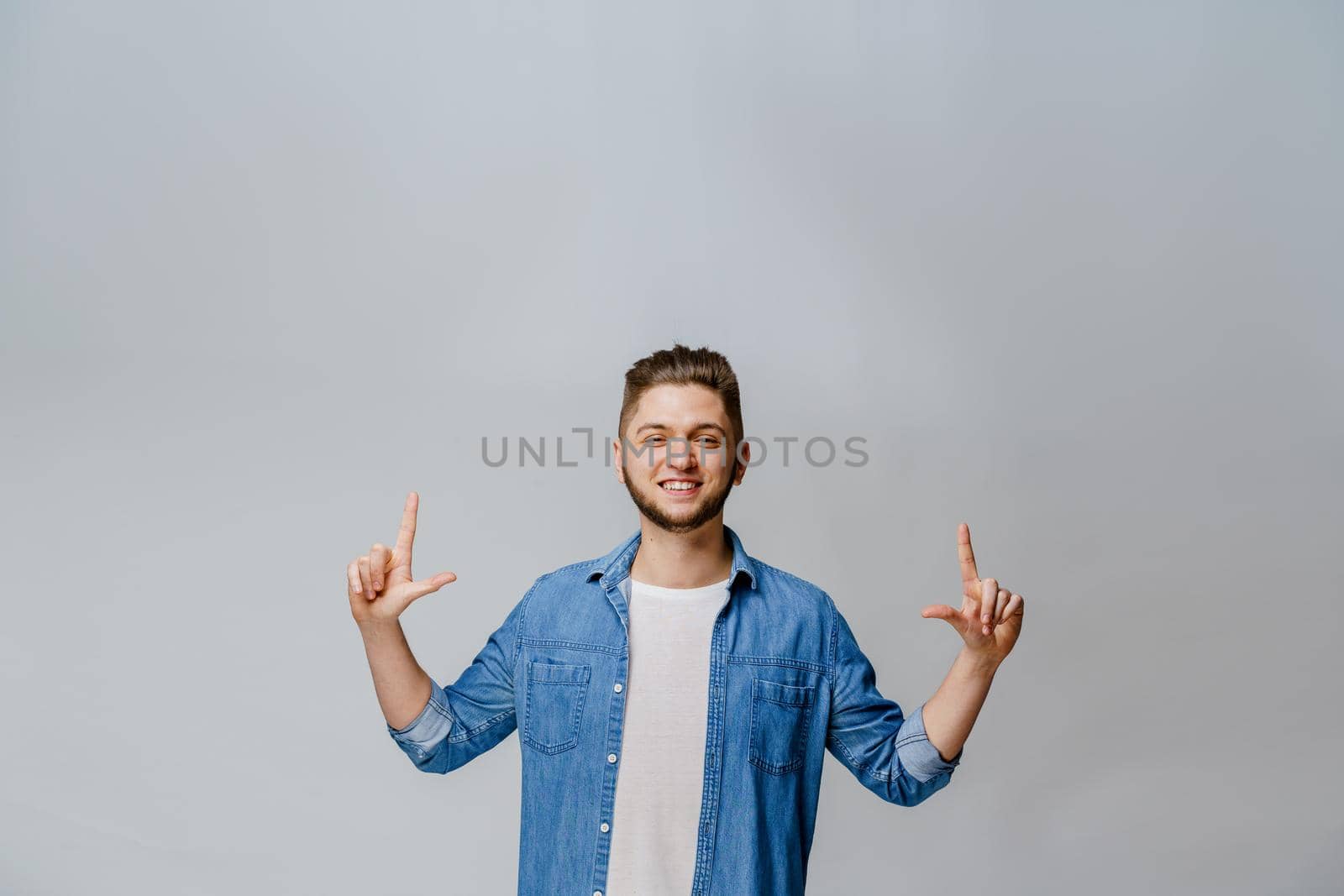 Pointing up. Emotional young handsome man points his fingers up for text of advertise. Empty space for advertise.