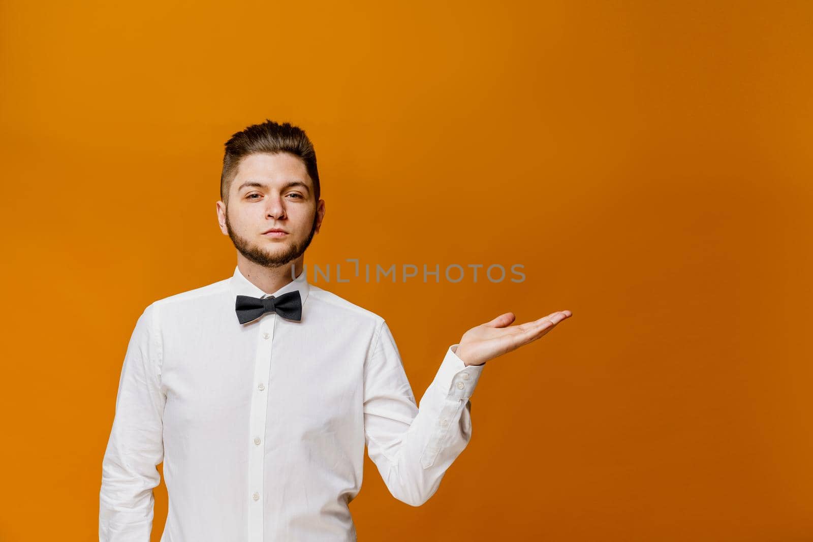 Easy choice. Professional model points to empty space for advertise of online business. Show man. Handsome man wears white shirt with butterfly. by Rabizo