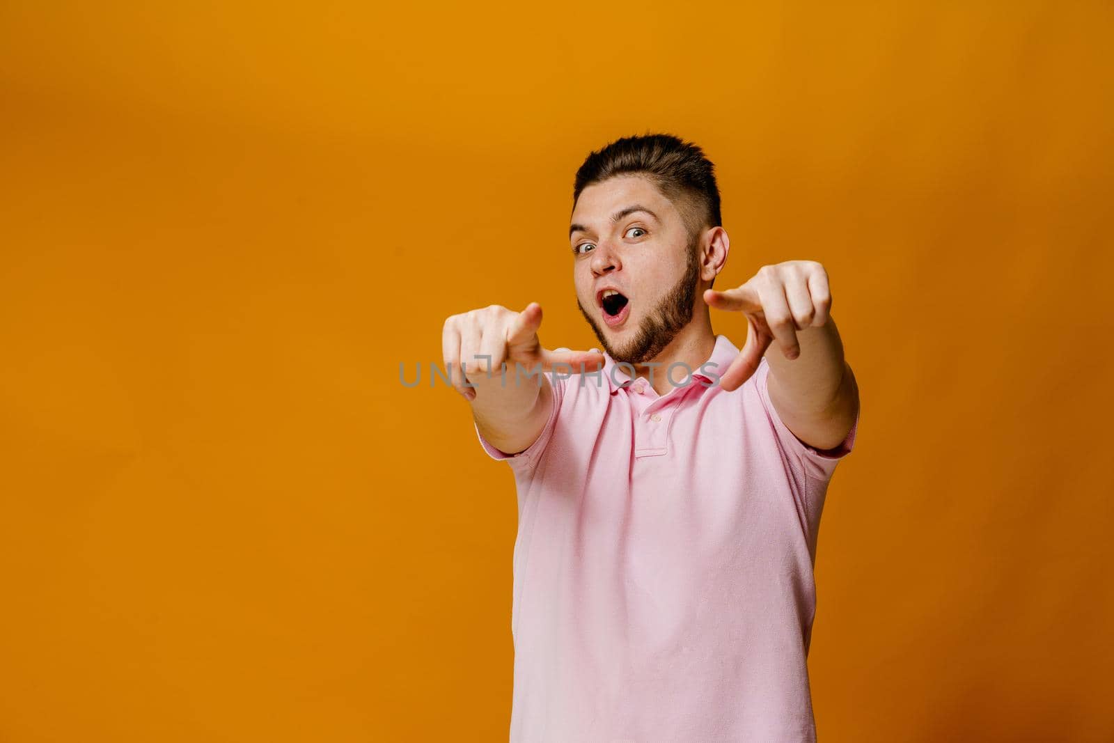 Handsome bearded caucasian man points to you. Confident man wears casual style and stands over orange backround. On-line business for students.