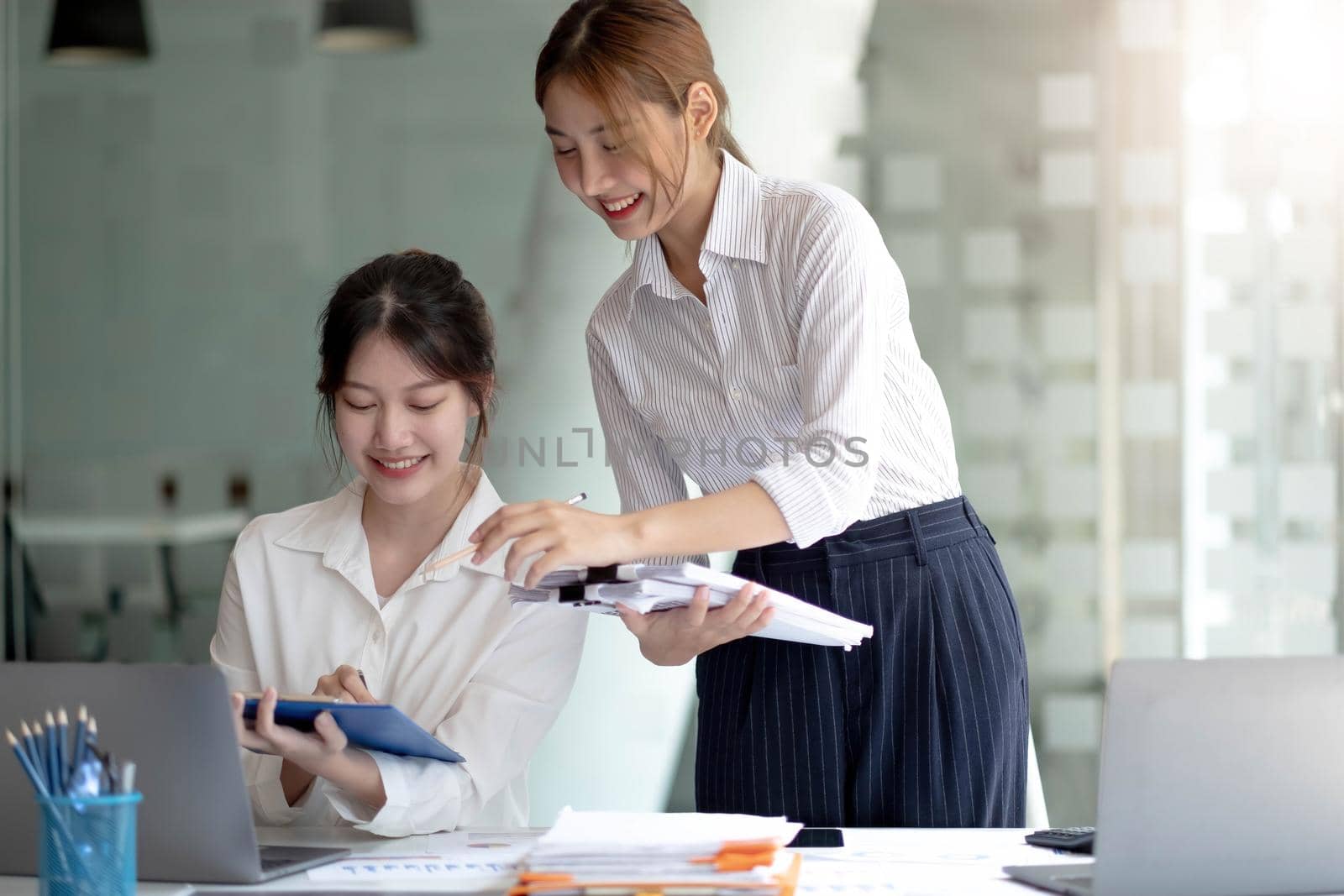 Two Young Asian businesswoman discuss with new startup project Idea presentation, analyze planning and financial statistics and investment market at office. by wichayada