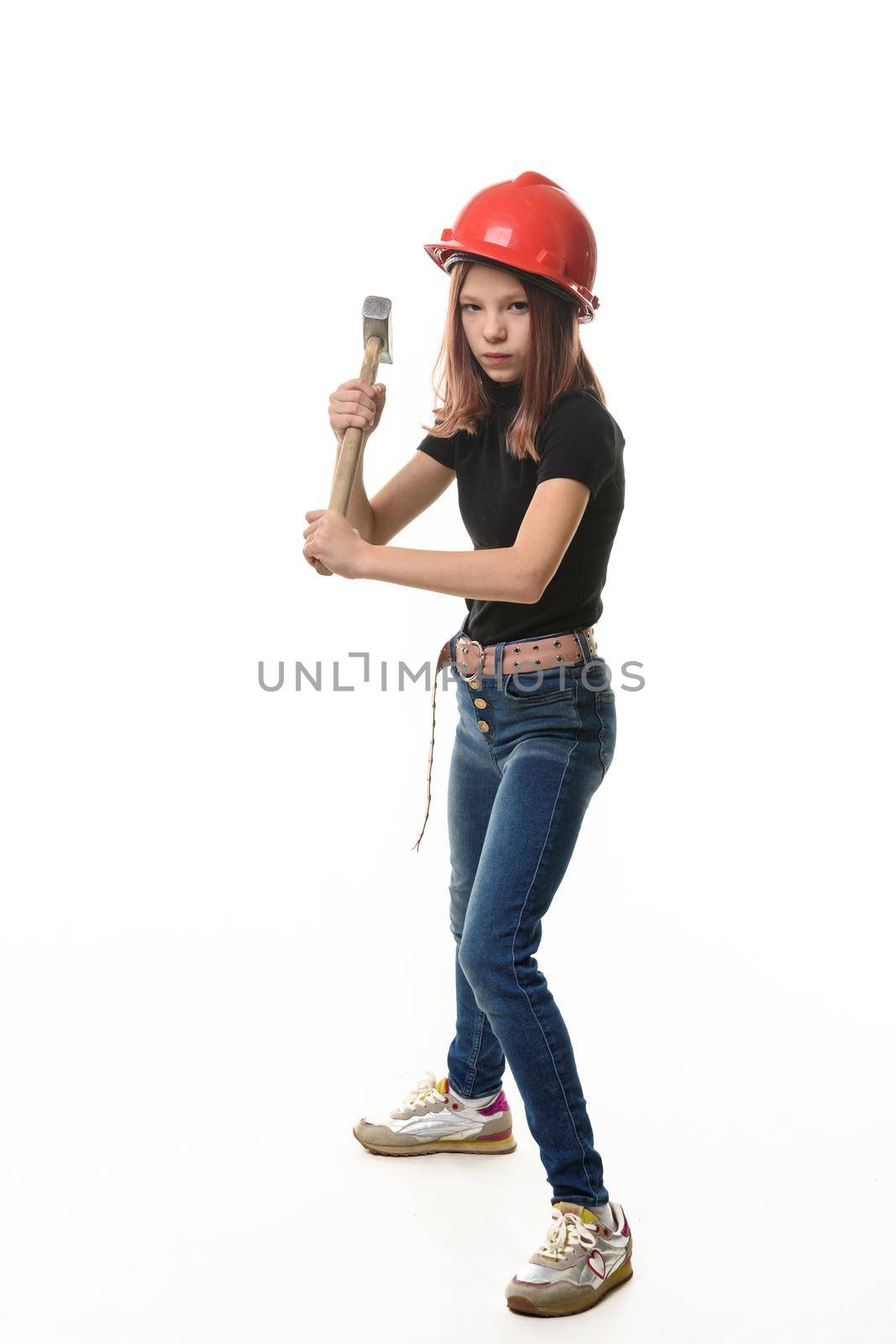 A girl in a hard hat is preparing to hit with a hammer, isolated on a white background
