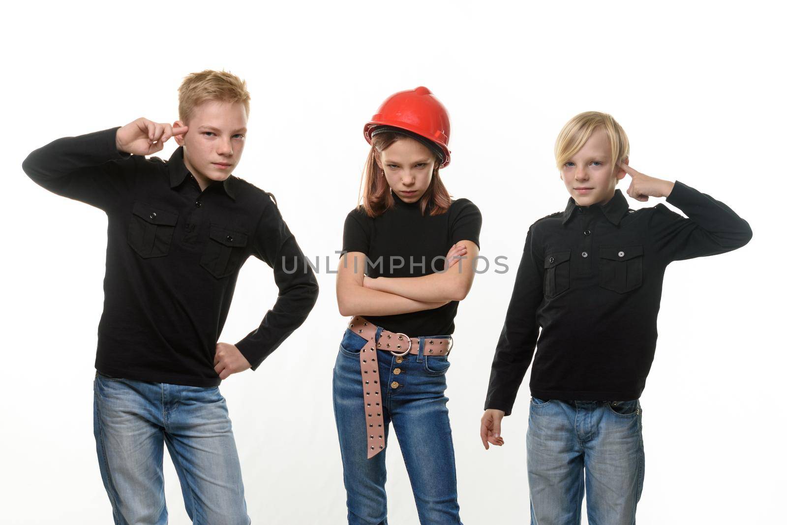 Two boys tease a girl, the girl is standing in a helmet in a helmet and puffed out her cheeks