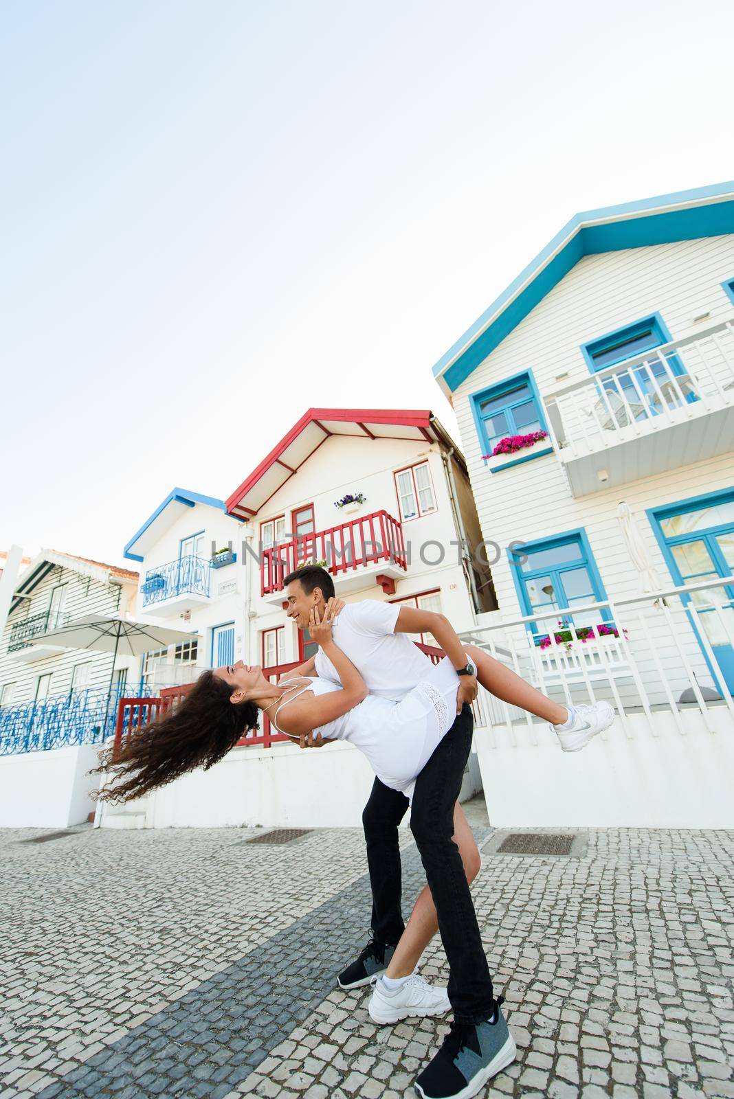 Young couple have fun and smiles and looks each others in Aveiro, Portugal near colourful and peaceful houses. Lifestyle. Having fun, laughs, smiles