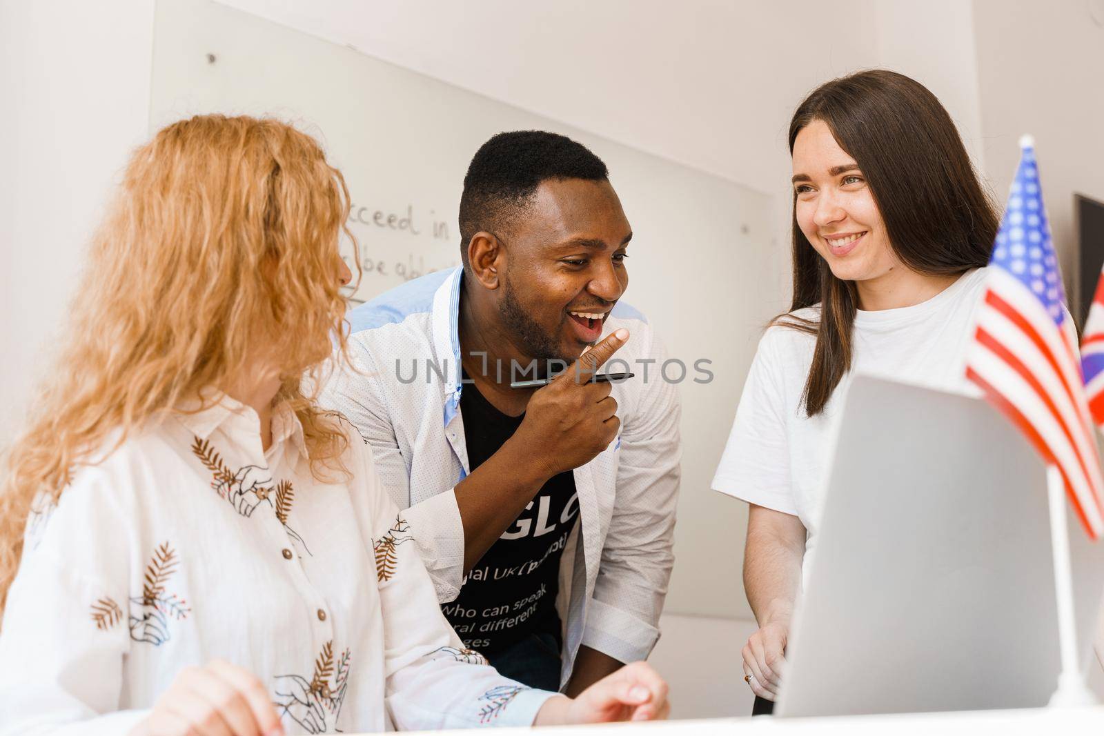 Online multiethnic attractive group of teachers study and laught, discuss something. Remote work in multinational group with laptop.