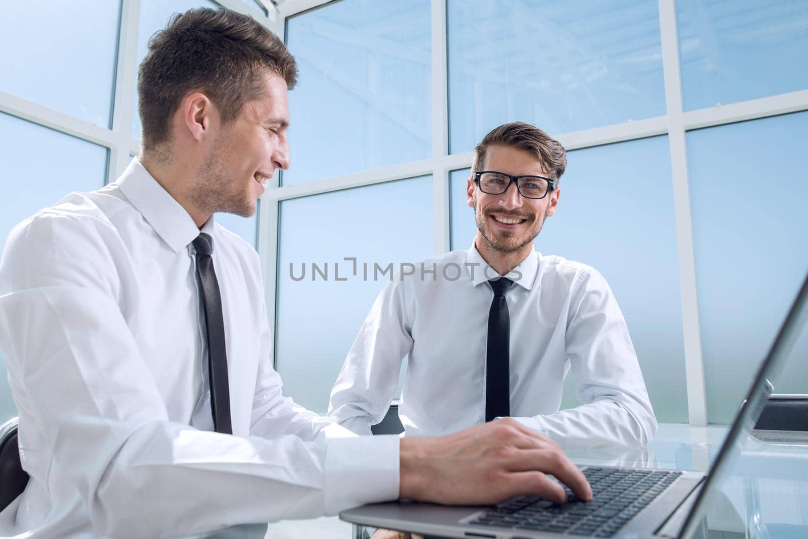 Two businessmen are sitting in the office and discussing the conclusion of a new deal