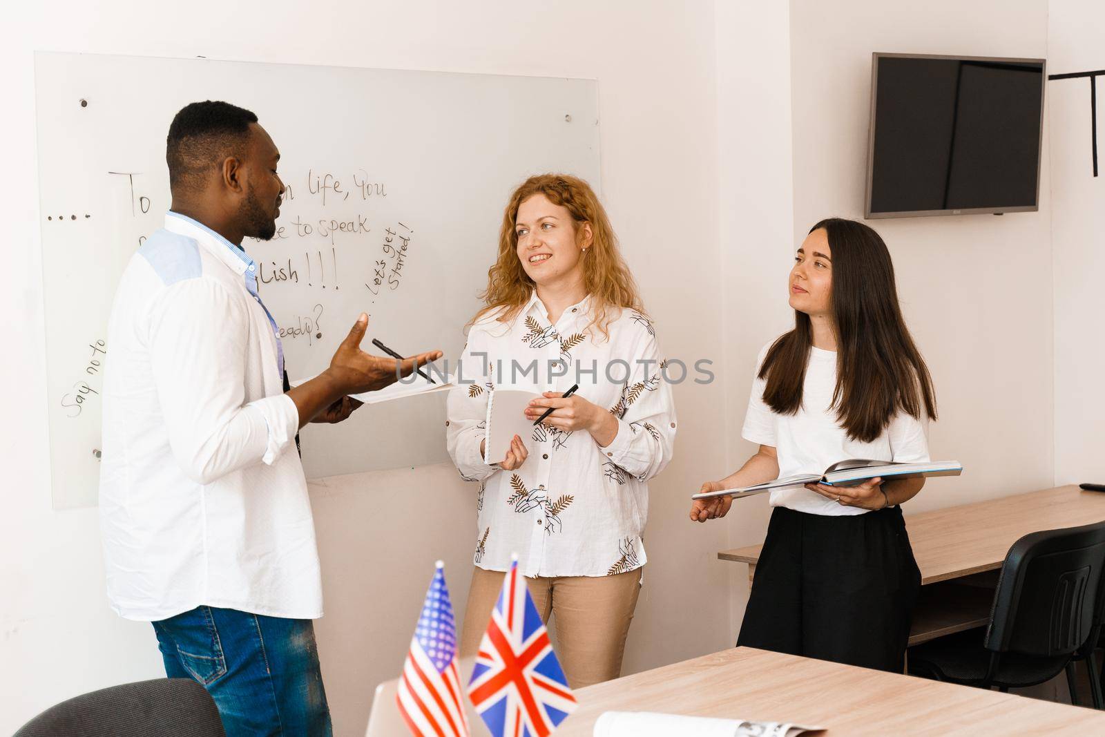 Multiethnic students and teacher study foreign languages together in class. Studing with laptop. Black handsome student study with white people together.
