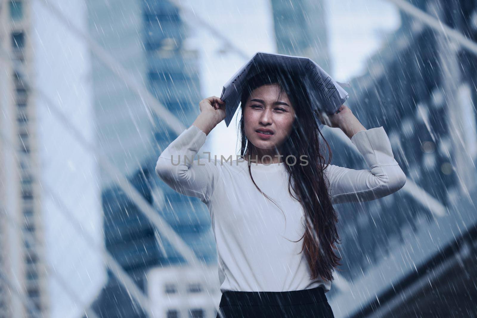 Girl in the heavy rain storm cover head with newspaper for economic obstacle passing concept.