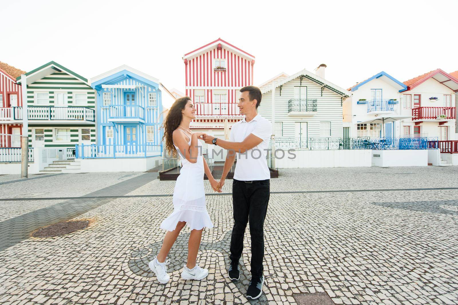 Young couple stays in tango pose and looks each others in Aveiro, Portugal near colourful and peaceful houses. Lifestyle. Having fun, by Rabizo
