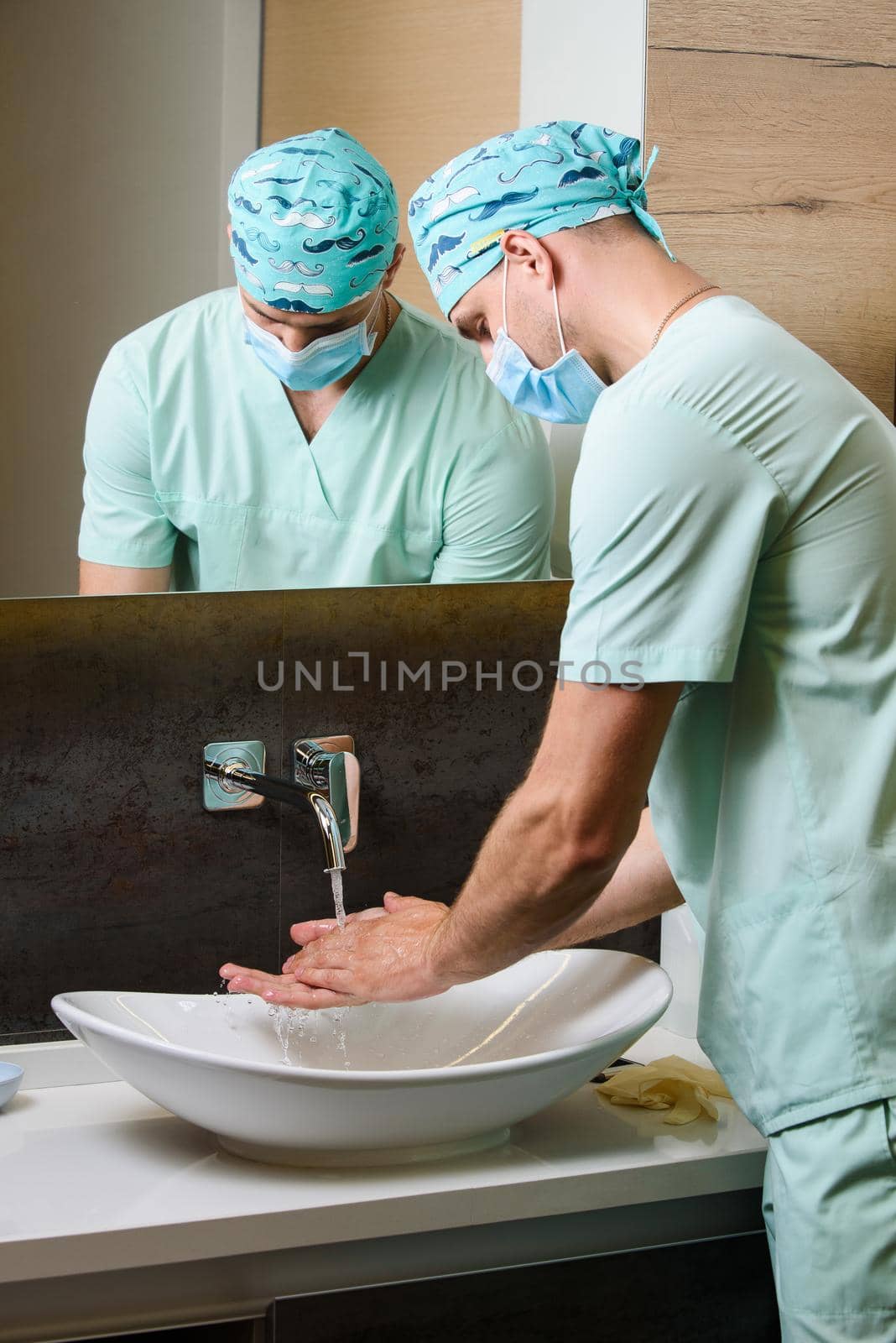 Doctors looks at the cleanliness of his hands after washing under a stream of water. Wash your hands under running water by Rabizo